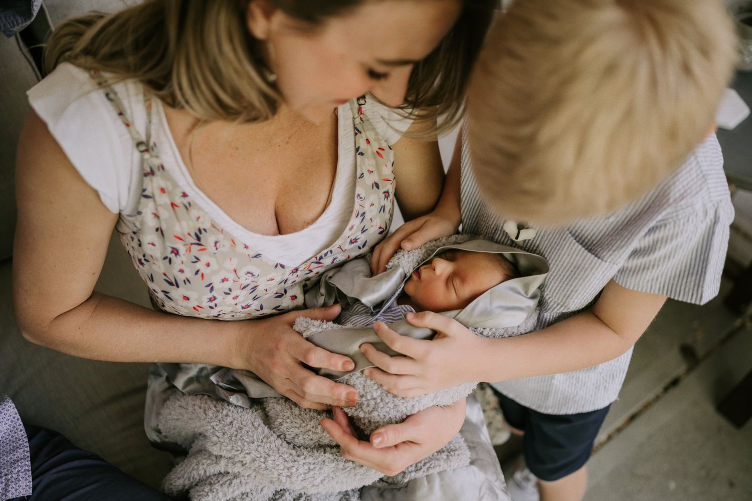 Intimate moment with newborn baby being held in soft natural lighting.