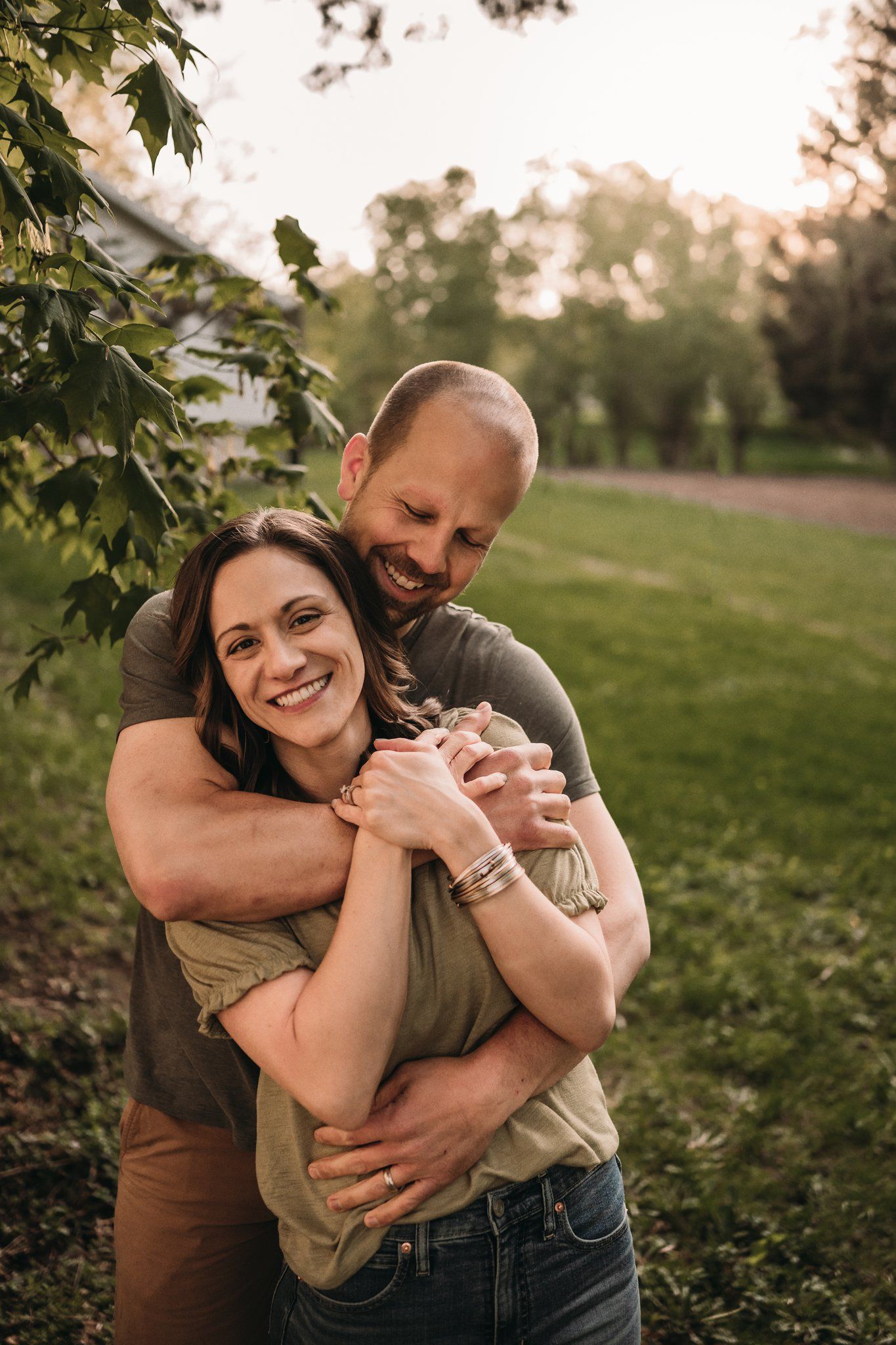 Joyful couple sharing a warm embrace in a sunlit park during golden hour.