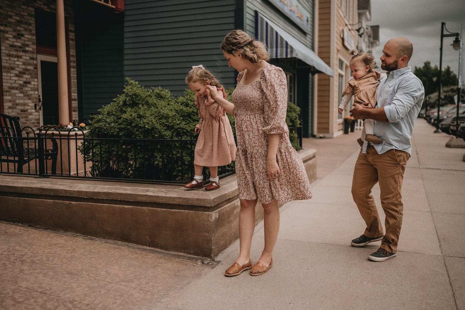 A family enjoying a playful moment together on an urban sidewalk wearing coordinated outfits.