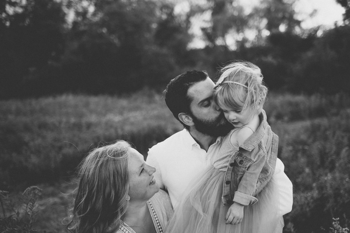 Black and white intimate family moment captured in a natural outdoor setting.