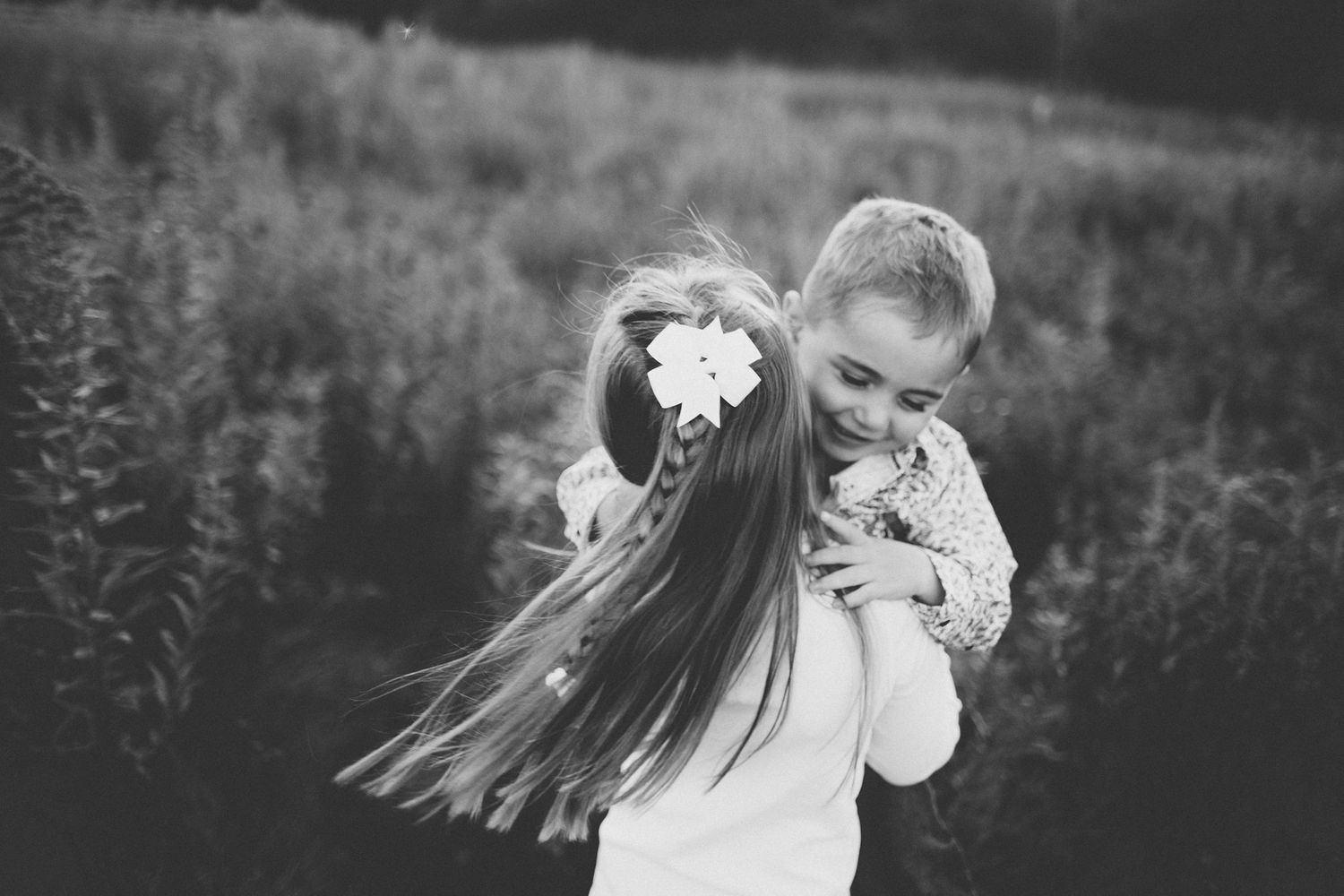 Two people sharing a joyful moment outdoors in a black and white photograph.