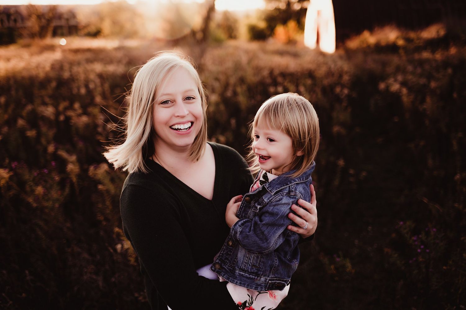 Candid moment of shared laughter between parent and child during golden hour photoshoot.