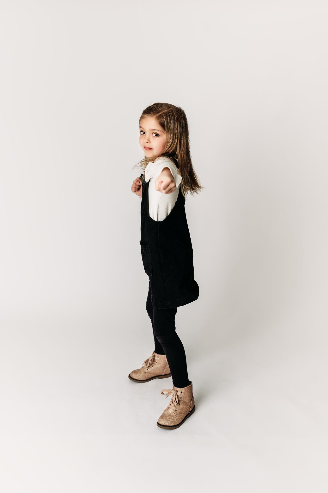Side profile of child in black and white outfit with tan boots against white background.