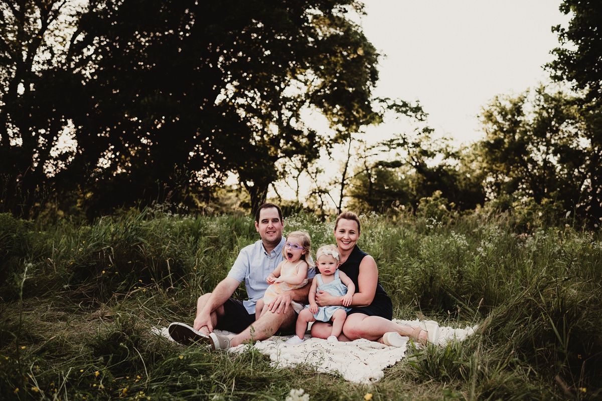 Family enjoying a summer evening photoshoot in tall grass.