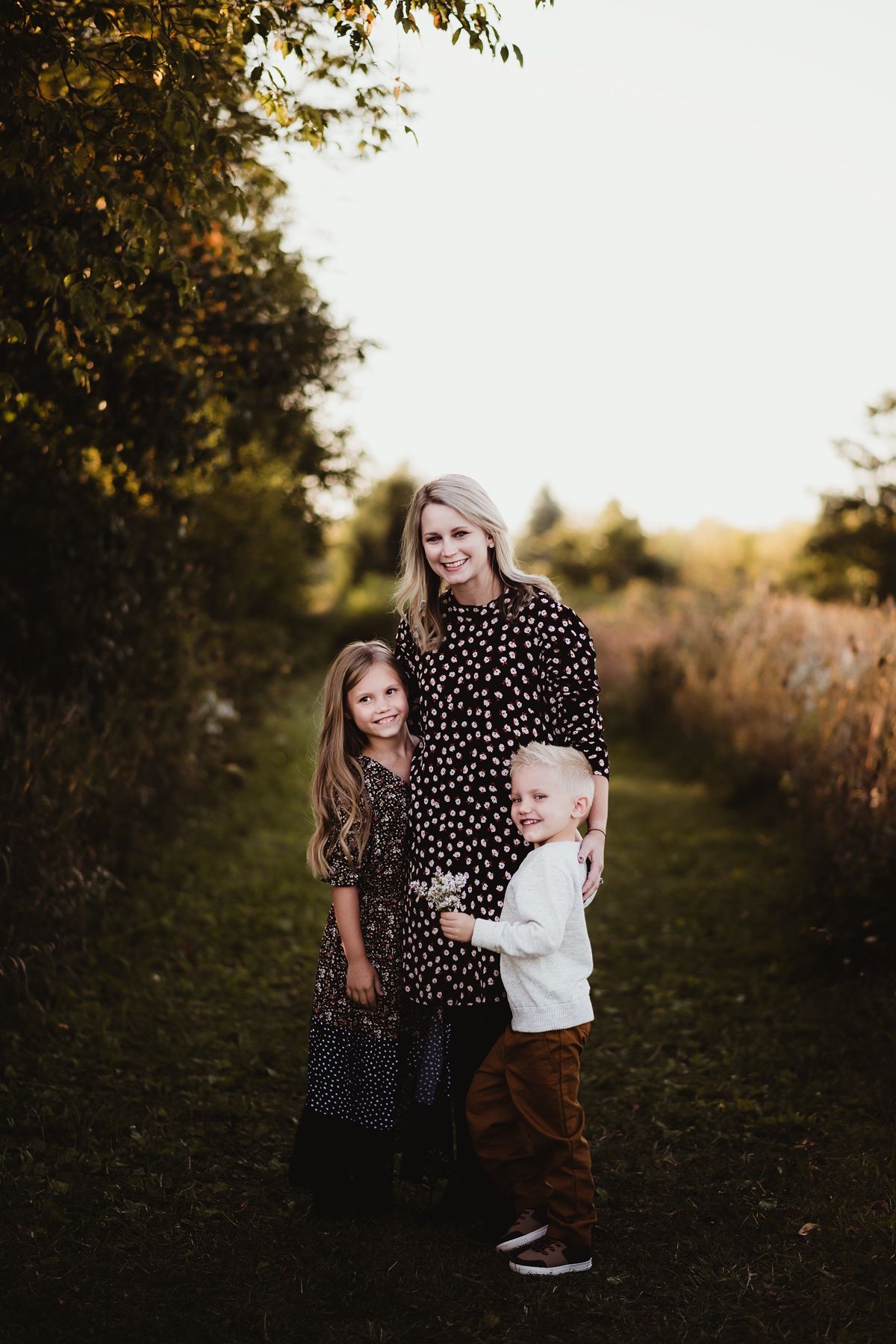 Family group portrait on nature path during golden hour.