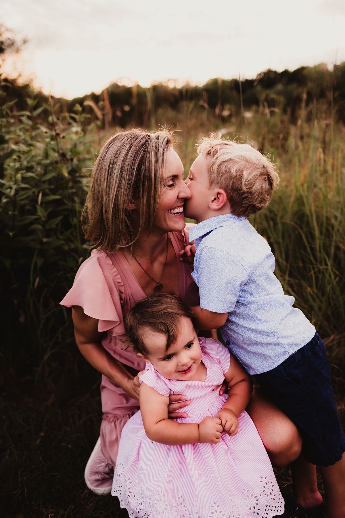 Sweet family moment outdoors with matching pink and blue outfits against natural backdrop.