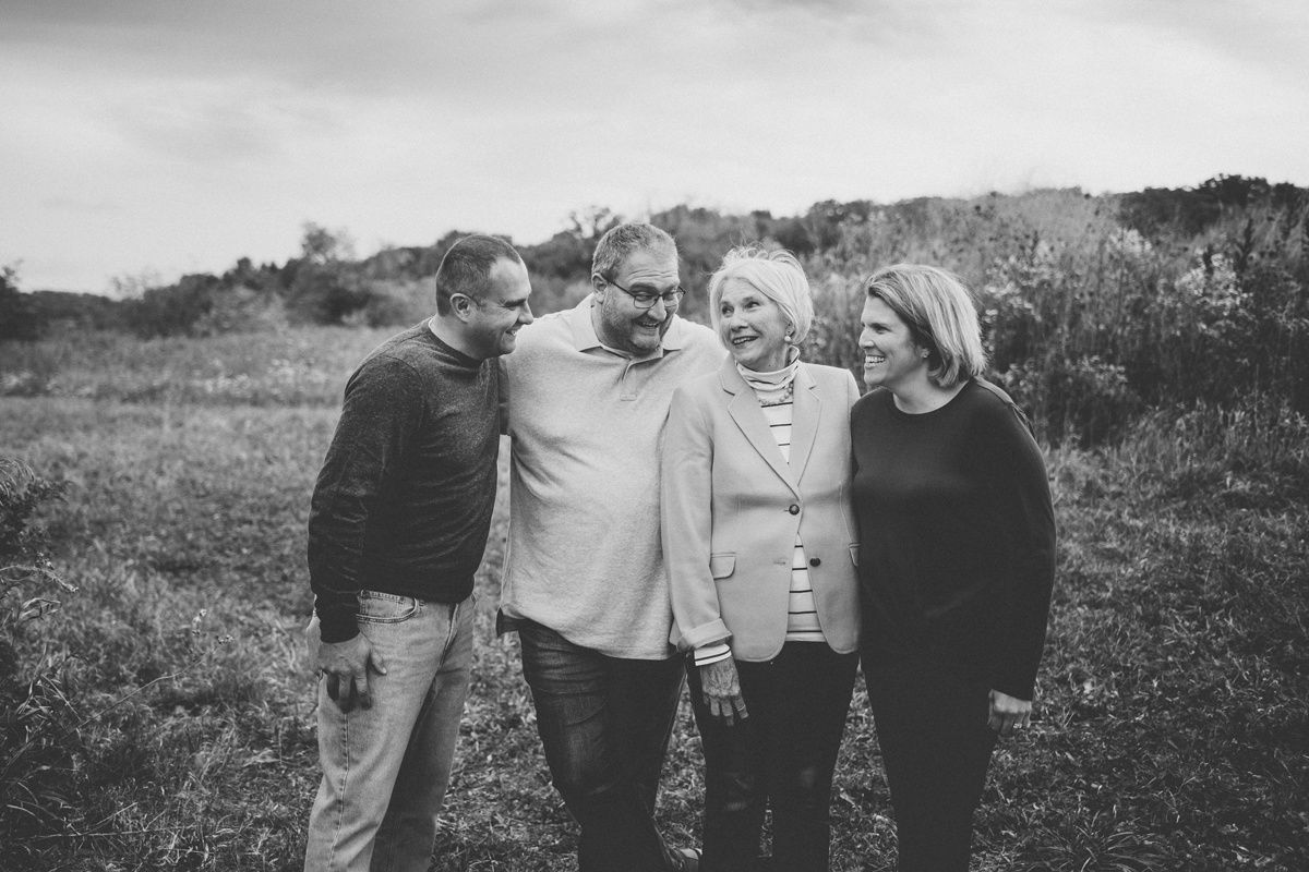 A black and white portrait of four people standing together in a natural outdoor setting.