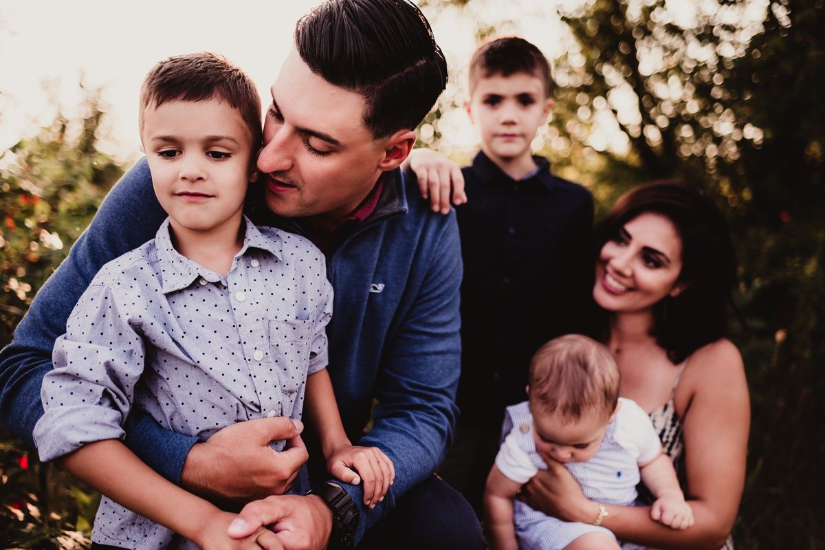 Outdoor family portrait of five people embracing during golden hour.