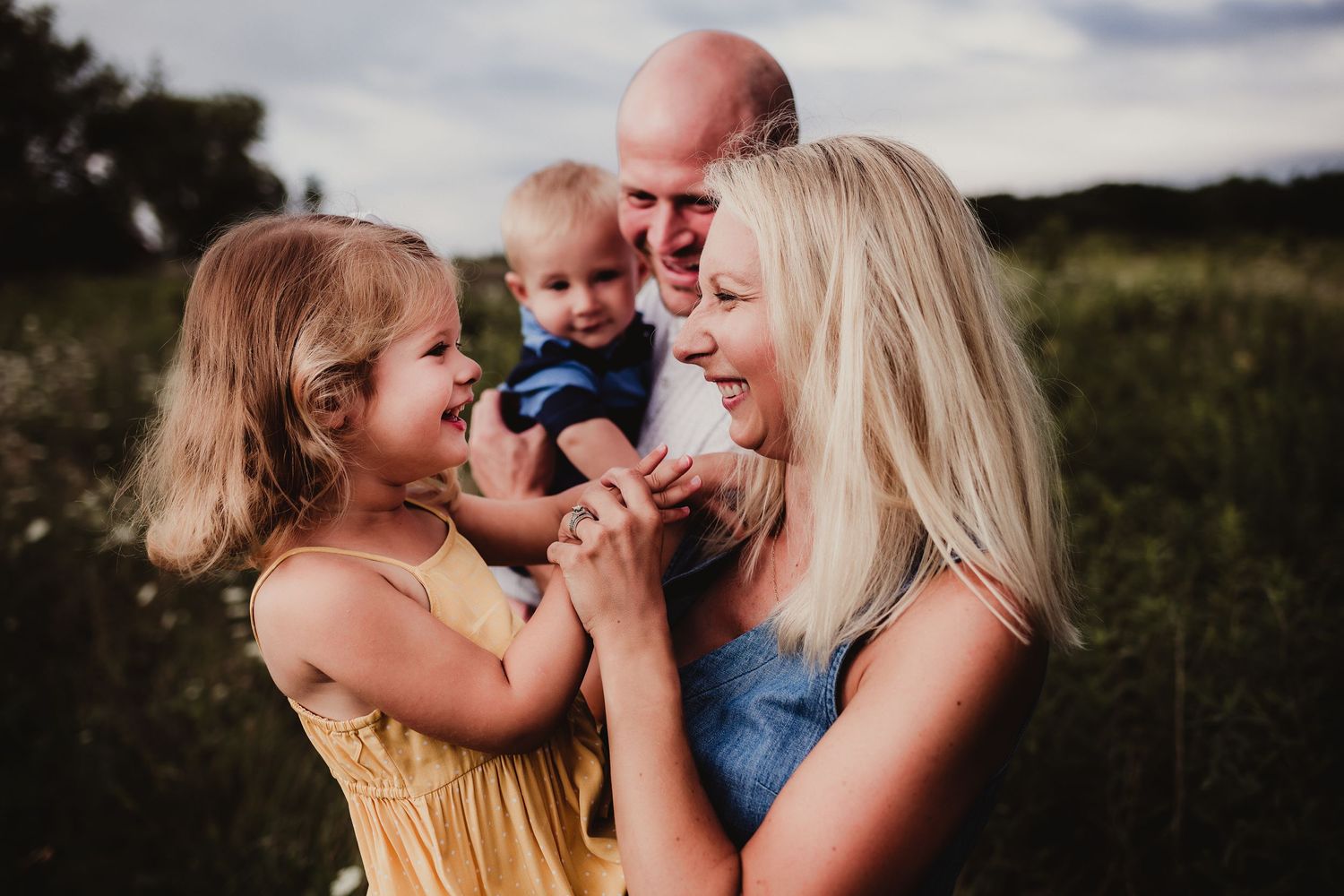 Candid family photo showing genuine laughter and joy in a sunset field.
