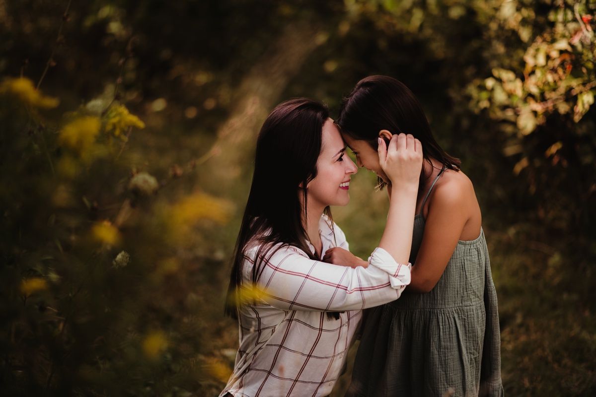 Intimate moment between mother and daughter sharing affection in nature setting.