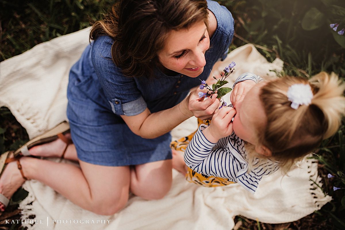Playful moment shared on a white blanket surrounded by spring flowers.