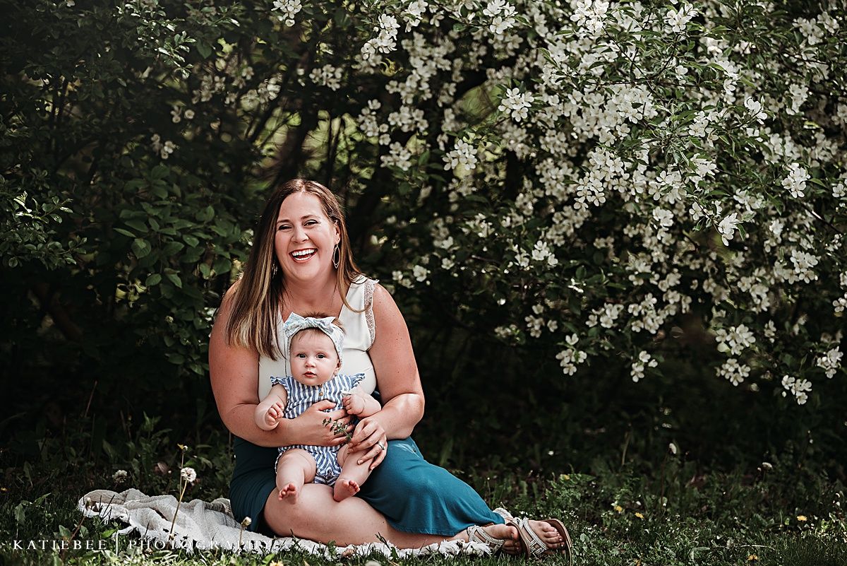 Candid outdoor family portrait with flowering bushes in the background.