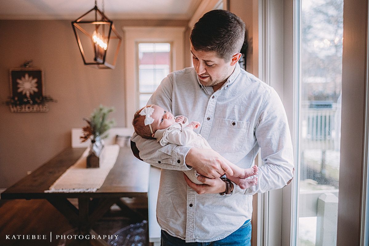 Interior family portrait showing tender moments beside large windows and decorative lantern lighting.