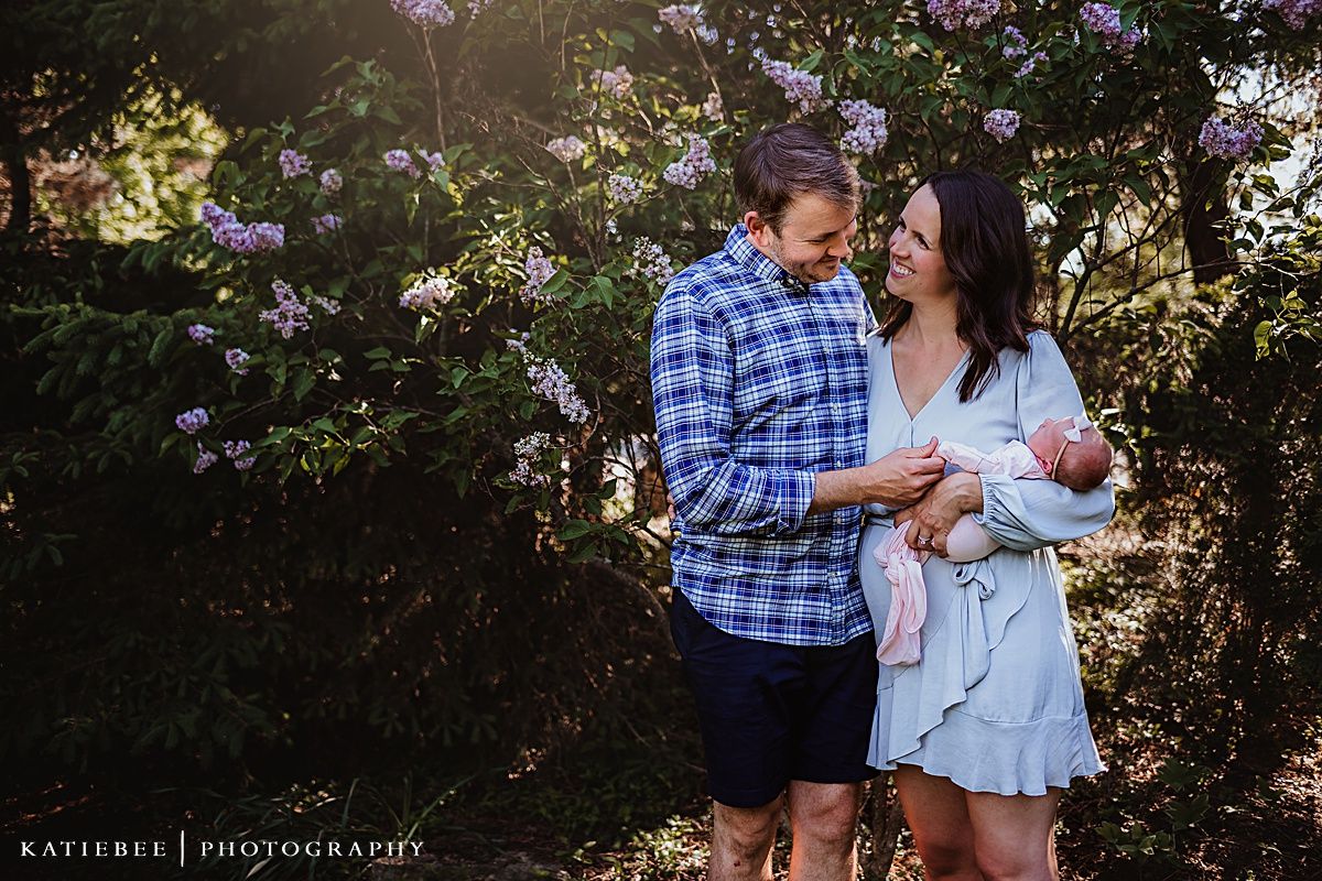 Romantic outdoor family portrait among blooming flowers and greenery.