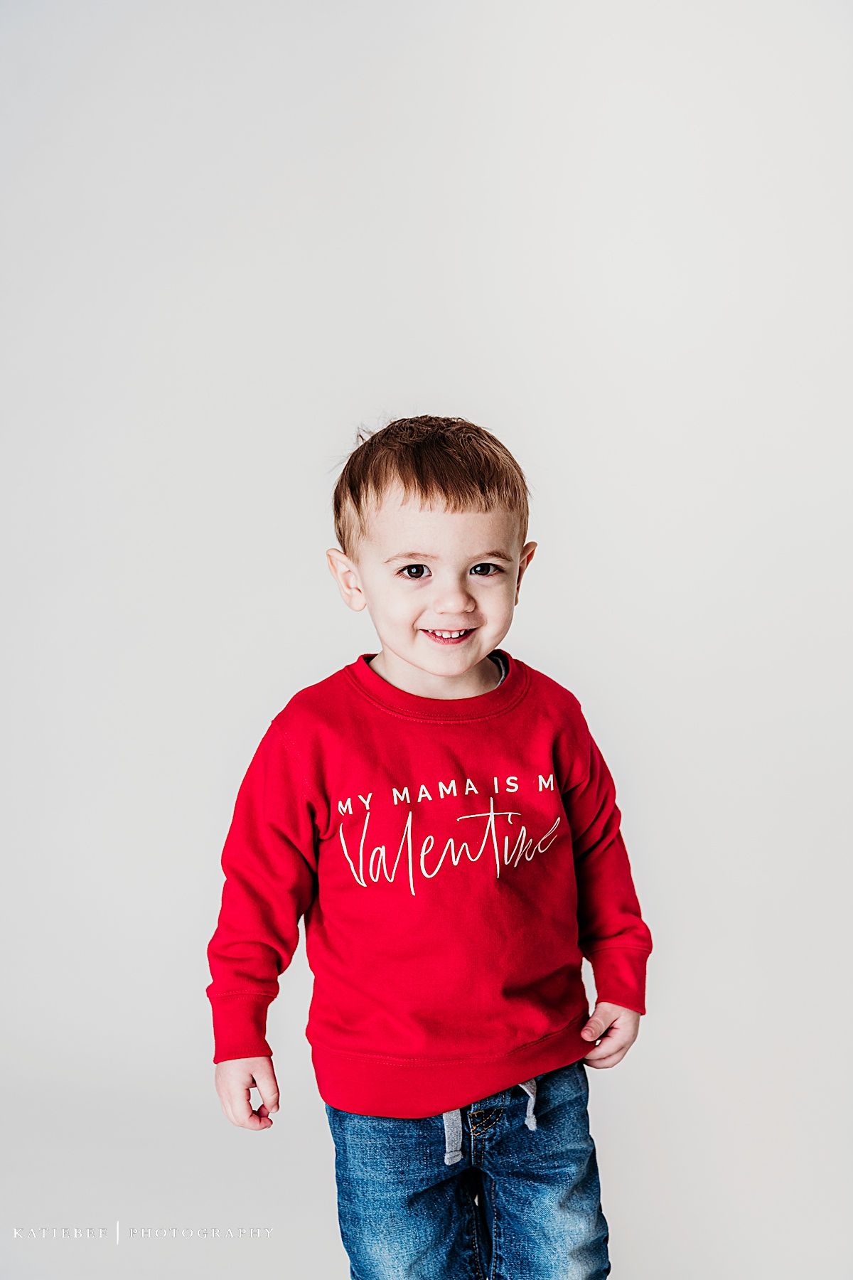 Adorable smile while wearing red valentine sweater against white background.