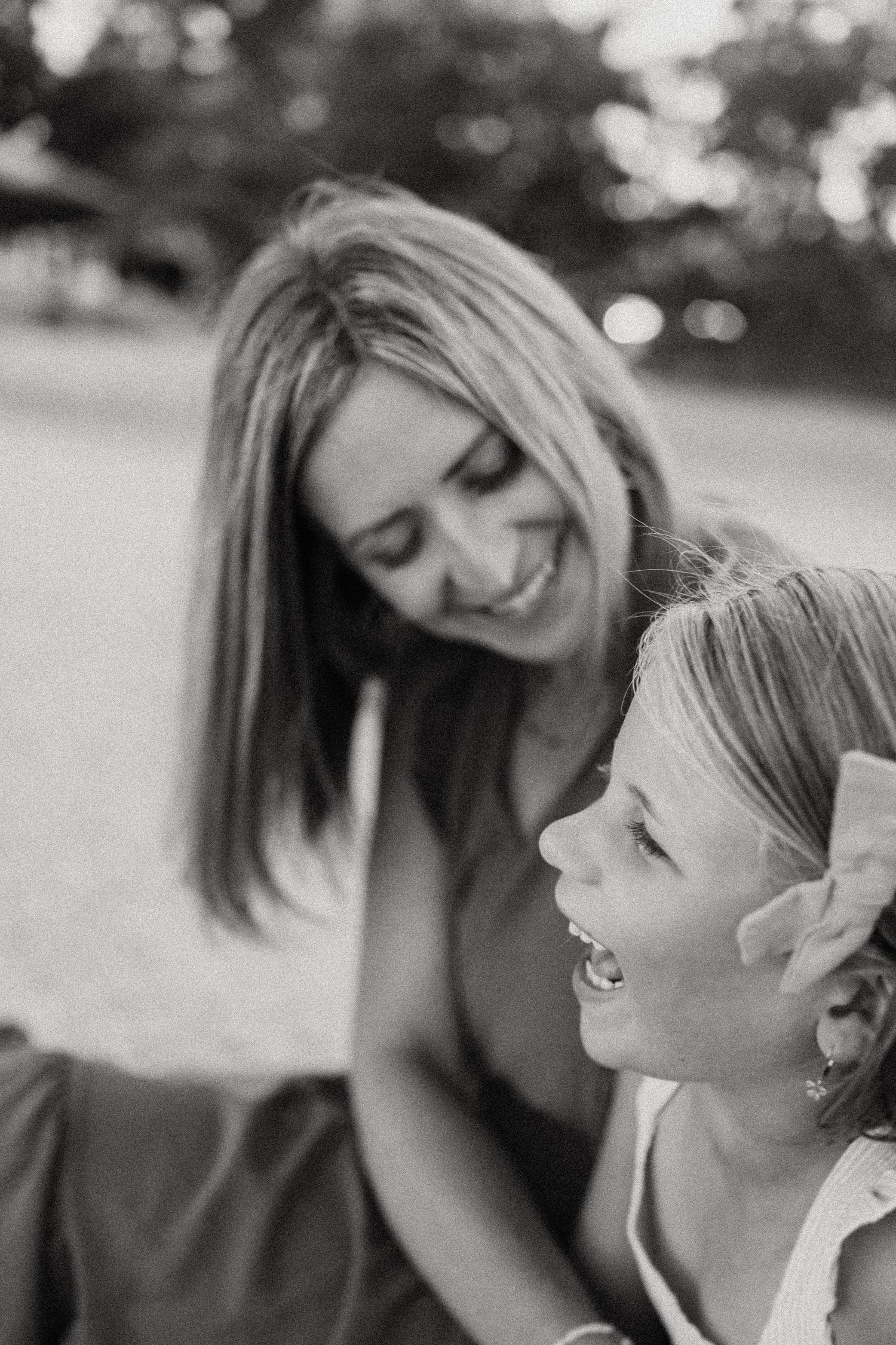 Black and white candid photo capturing genuine laughter and joy in an outdoor setting.