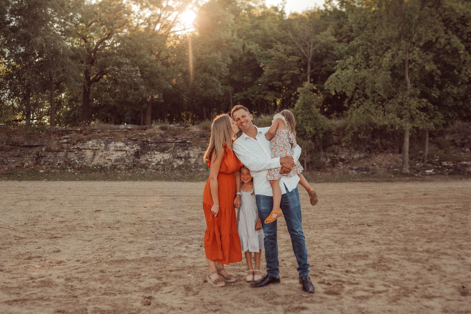 A family embraces during golden hour in a rustic outdoor setting.