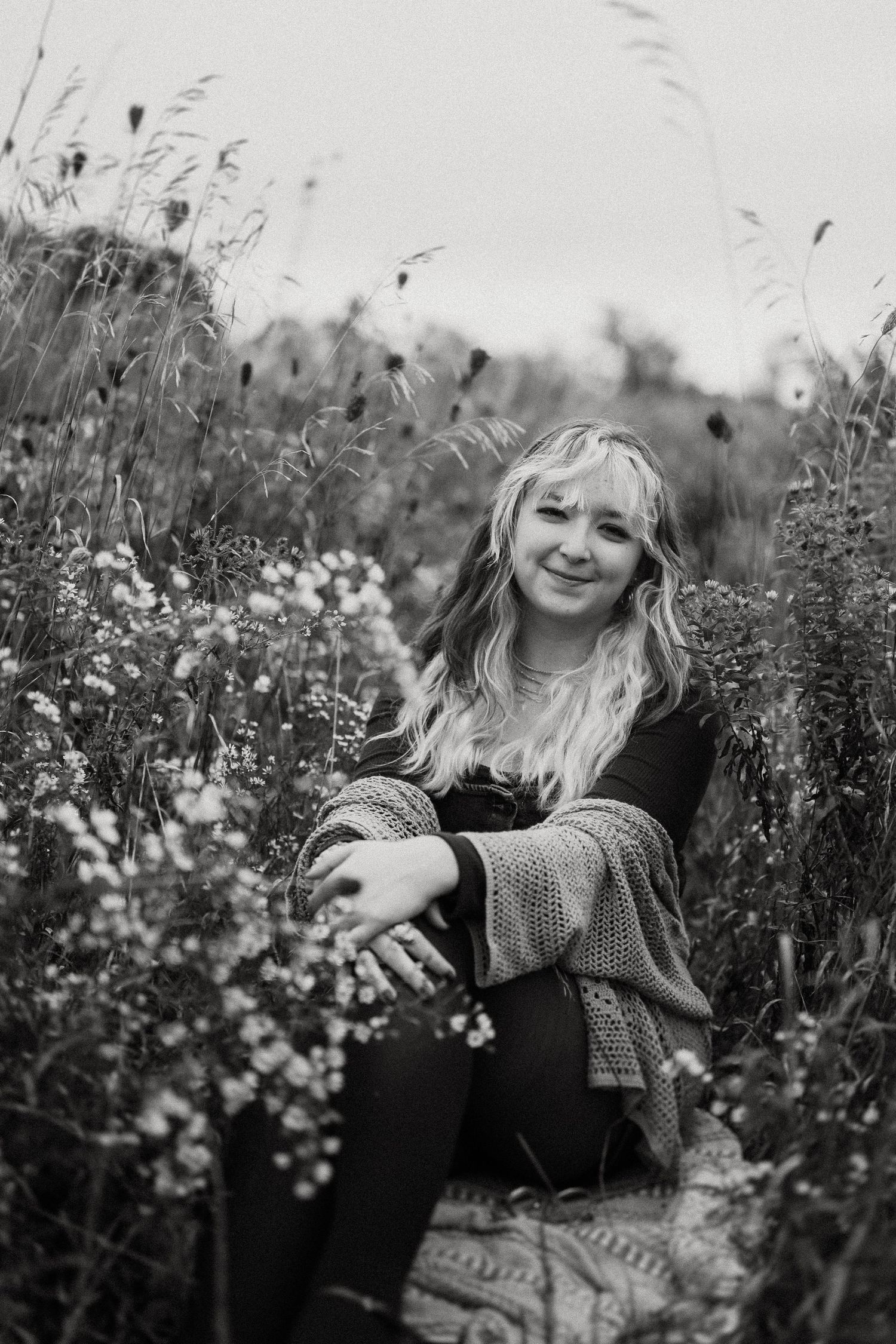 Monochrome portrait in a wild meadow with wispy grasses and delicate flowers.