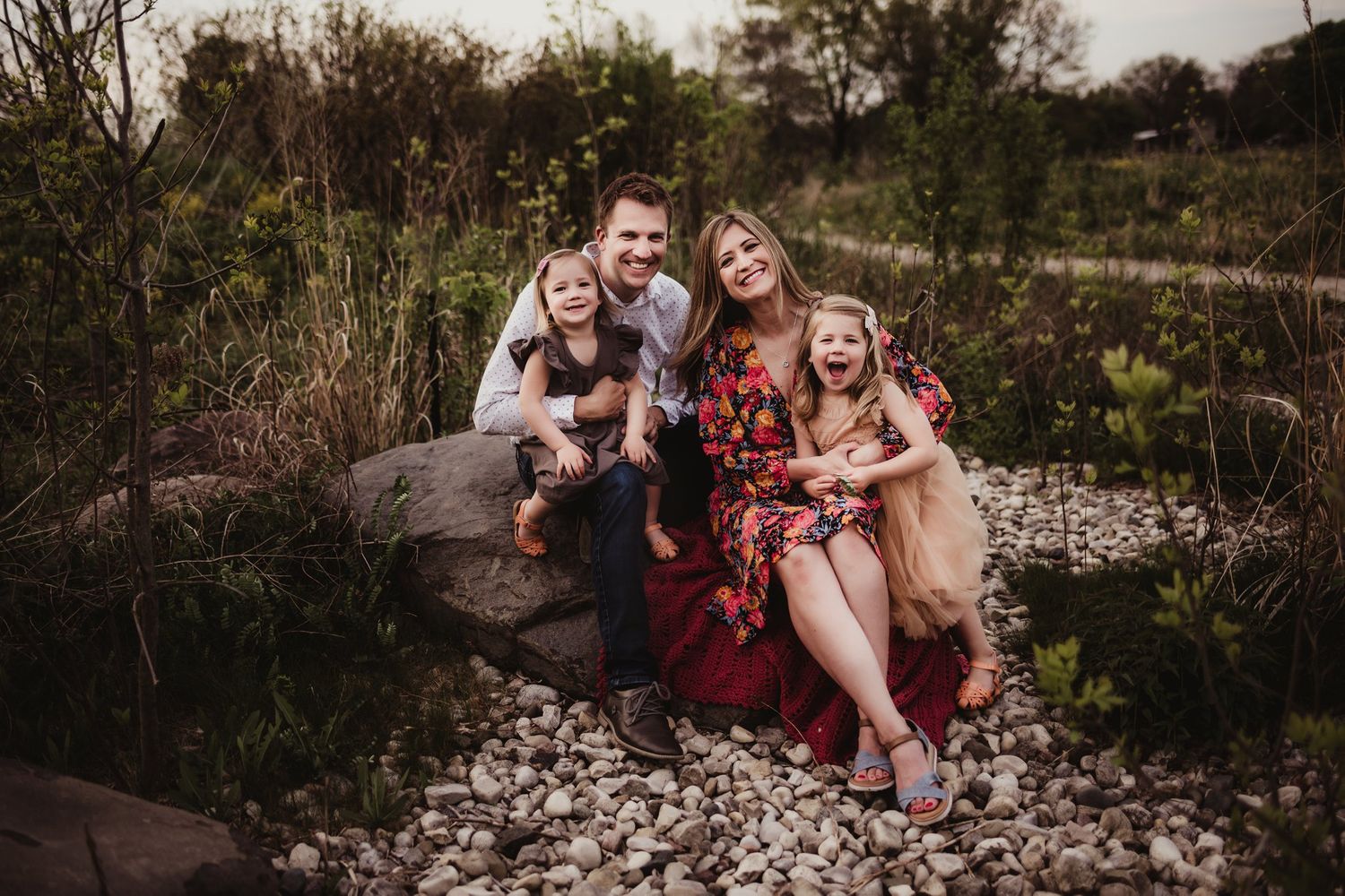 Natural family portrait session on rocky landscape during golden hour.