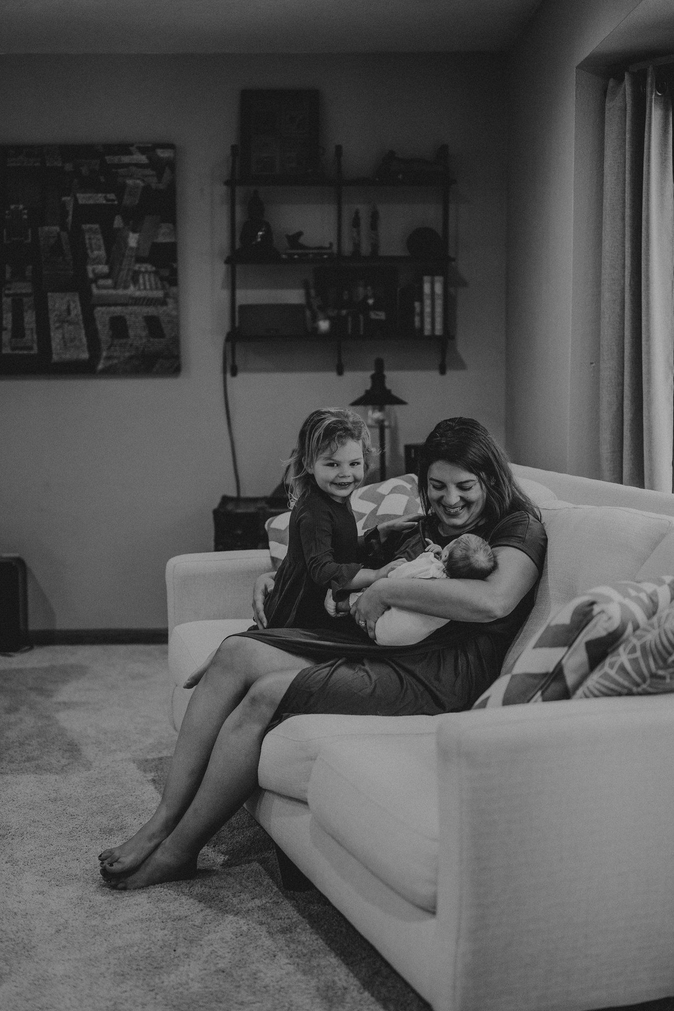 Black and white portrait of a family sharing an intimate moment on their living room couch.
