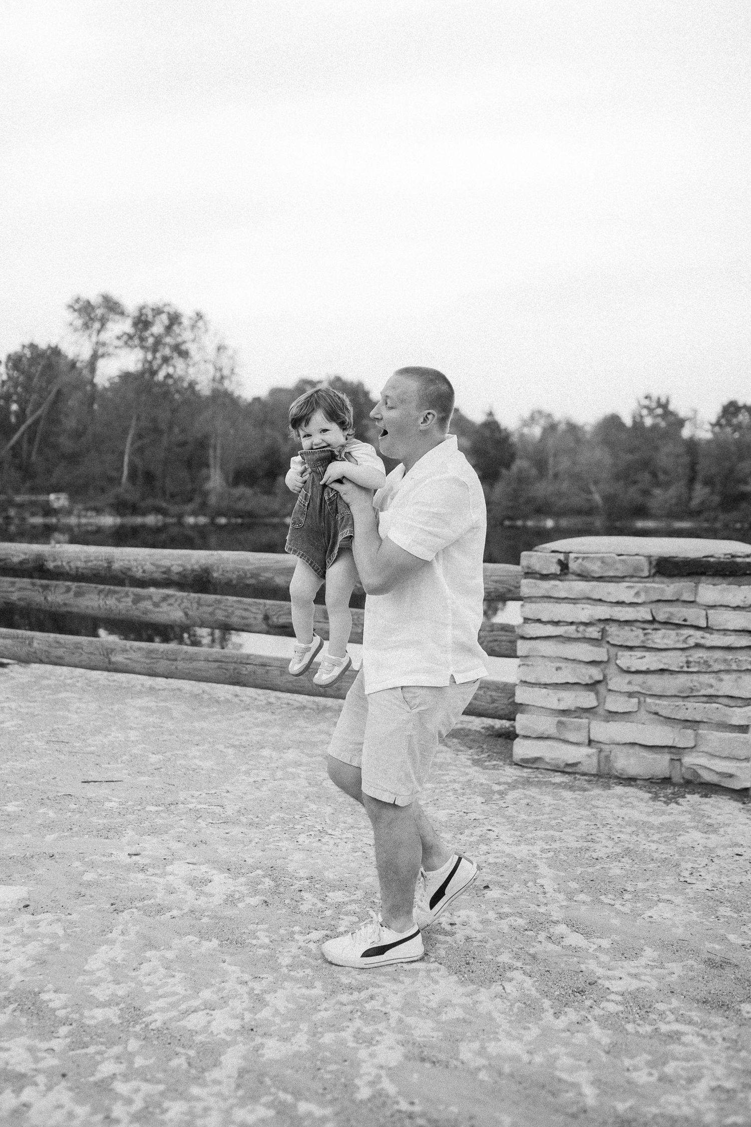 Series showing parent and child playing on stone wall in black and white photography.