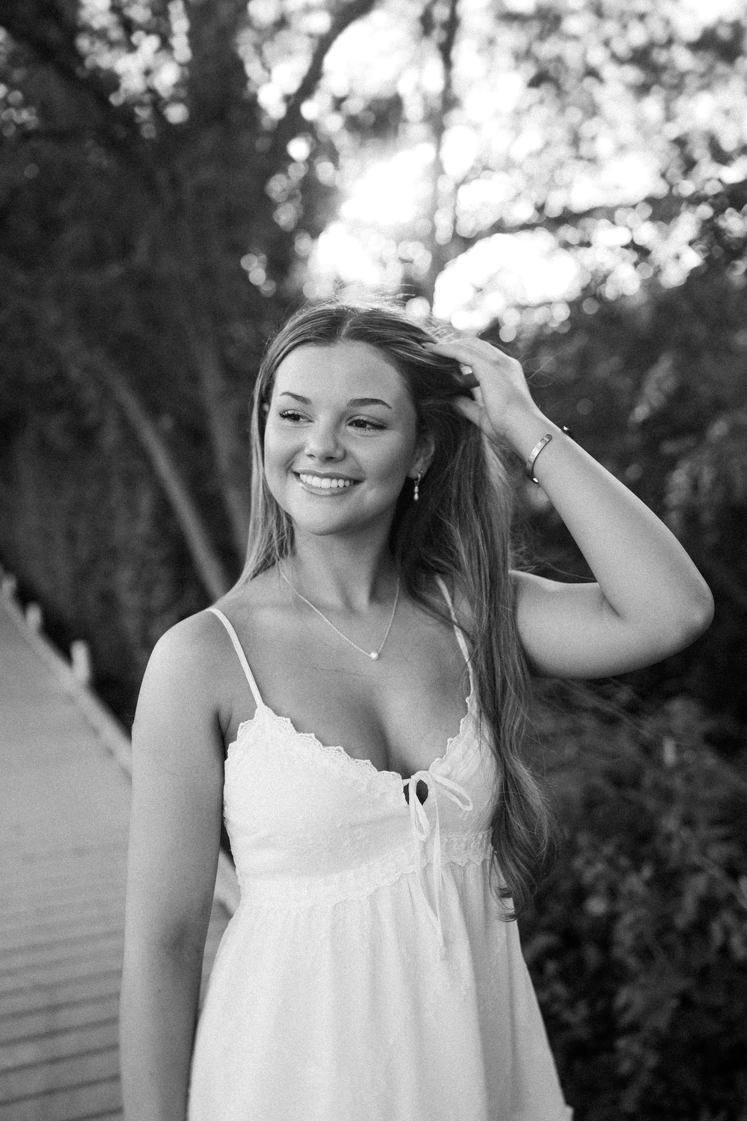 A black and white portrait captured on a wooden boardwalk with natural evening light.