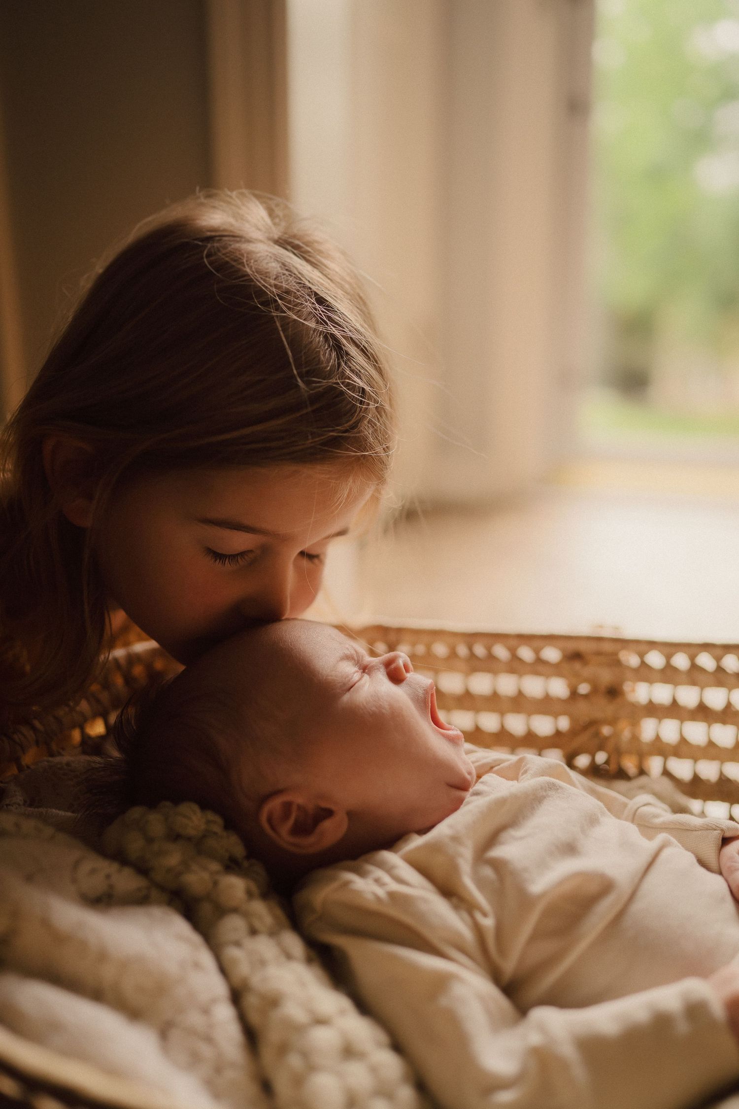 Intimate moment between parent and baby in warm sunlit room with soft textiles.