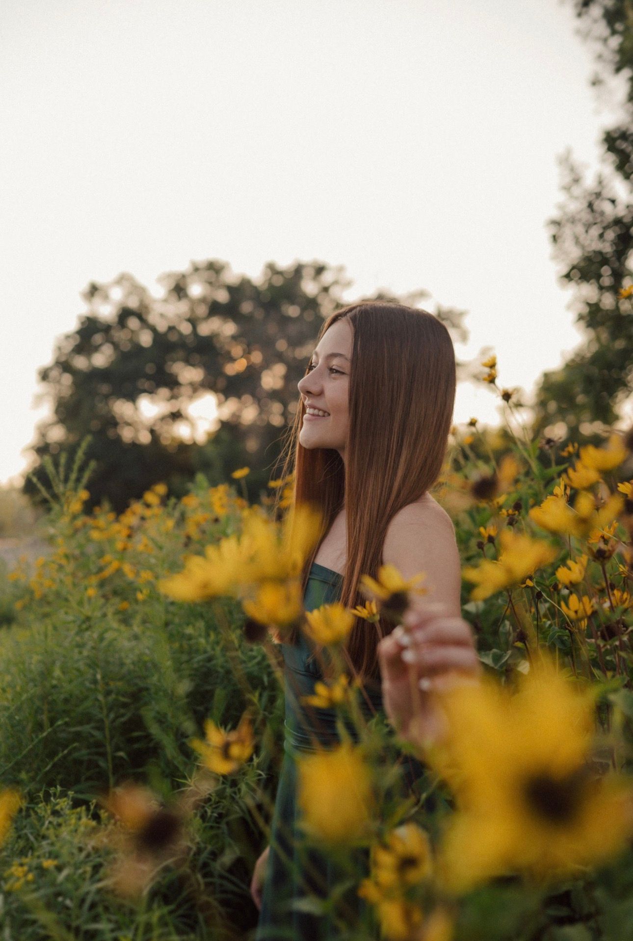 Ethereal portrait in a field of yellow wildflowers during golden hour.