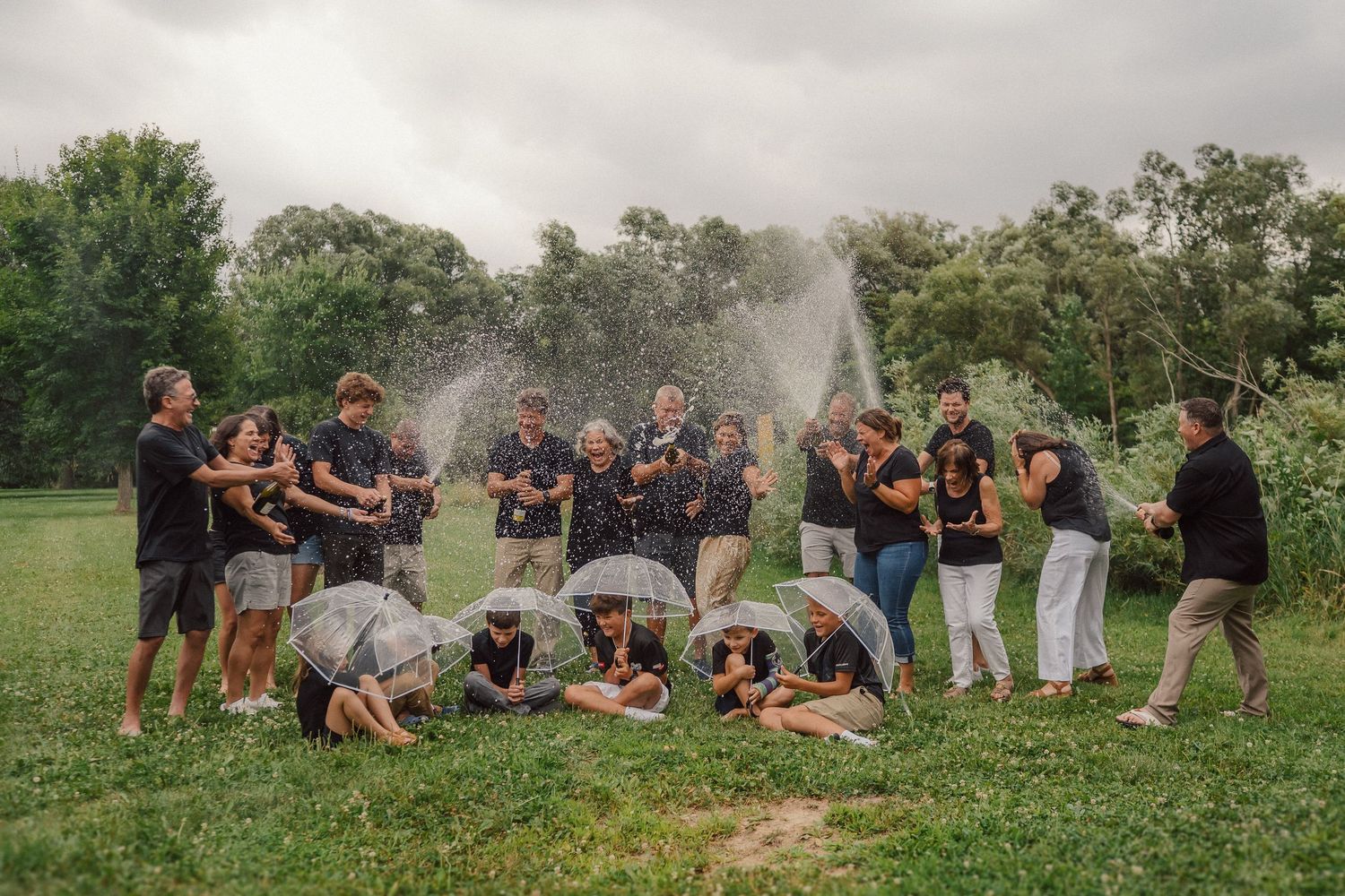 A group of people on a grassy field spraying champagne and celebrating.