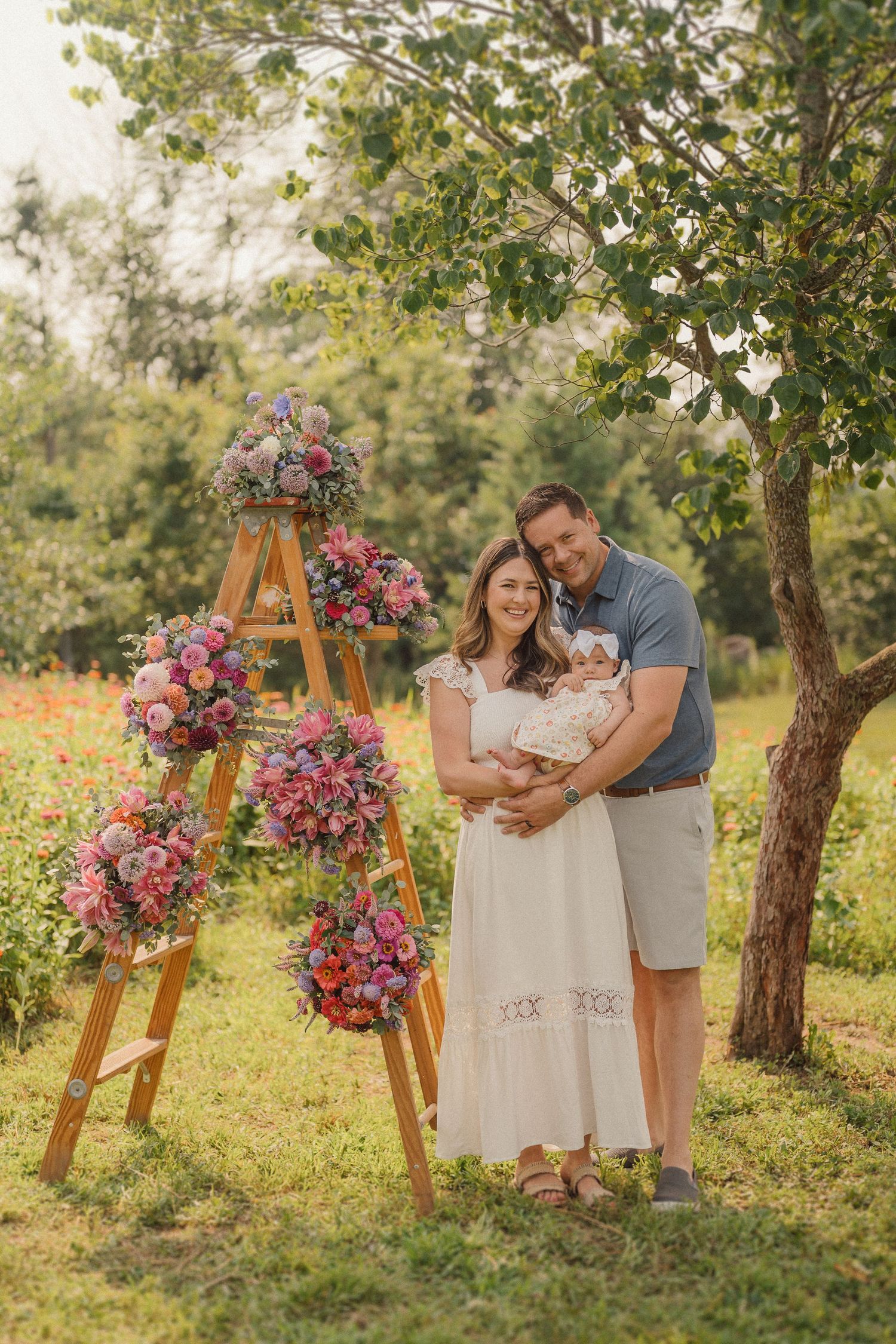 A family portrait in a spring garden with a ladder decorated with pink and purple floral arrangements.