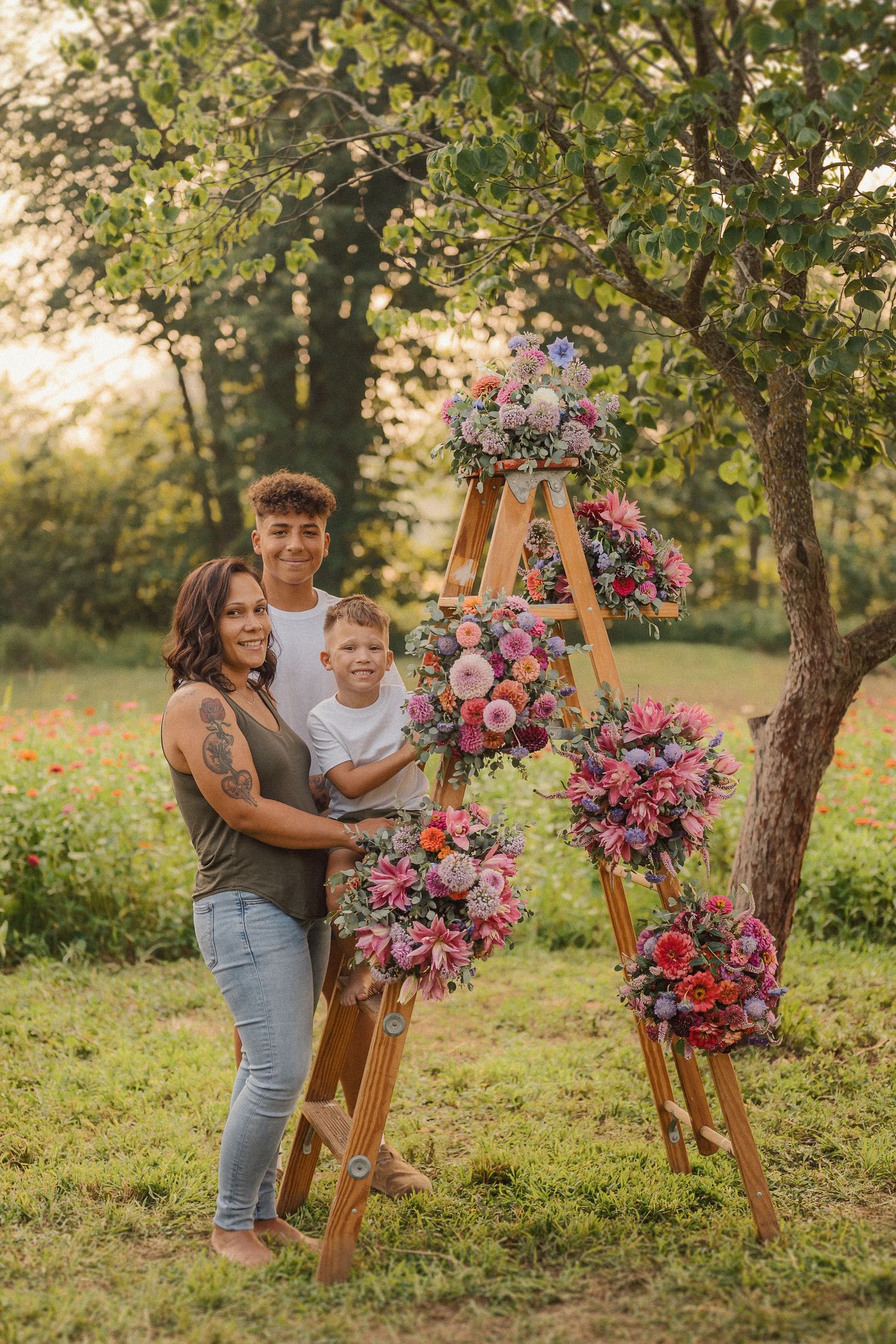 Wooden ladder adorned with vibrant pink and purple floral arrangements creates a stunning outdoor display in a garden setting.