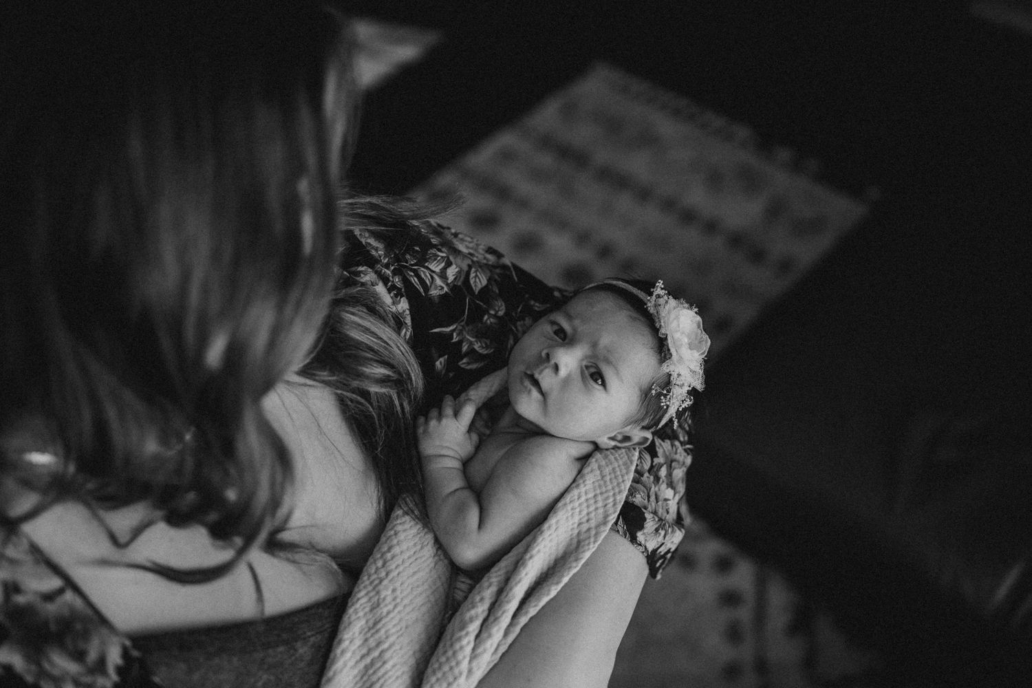 Black and white portrait of a baby with small flower headband.