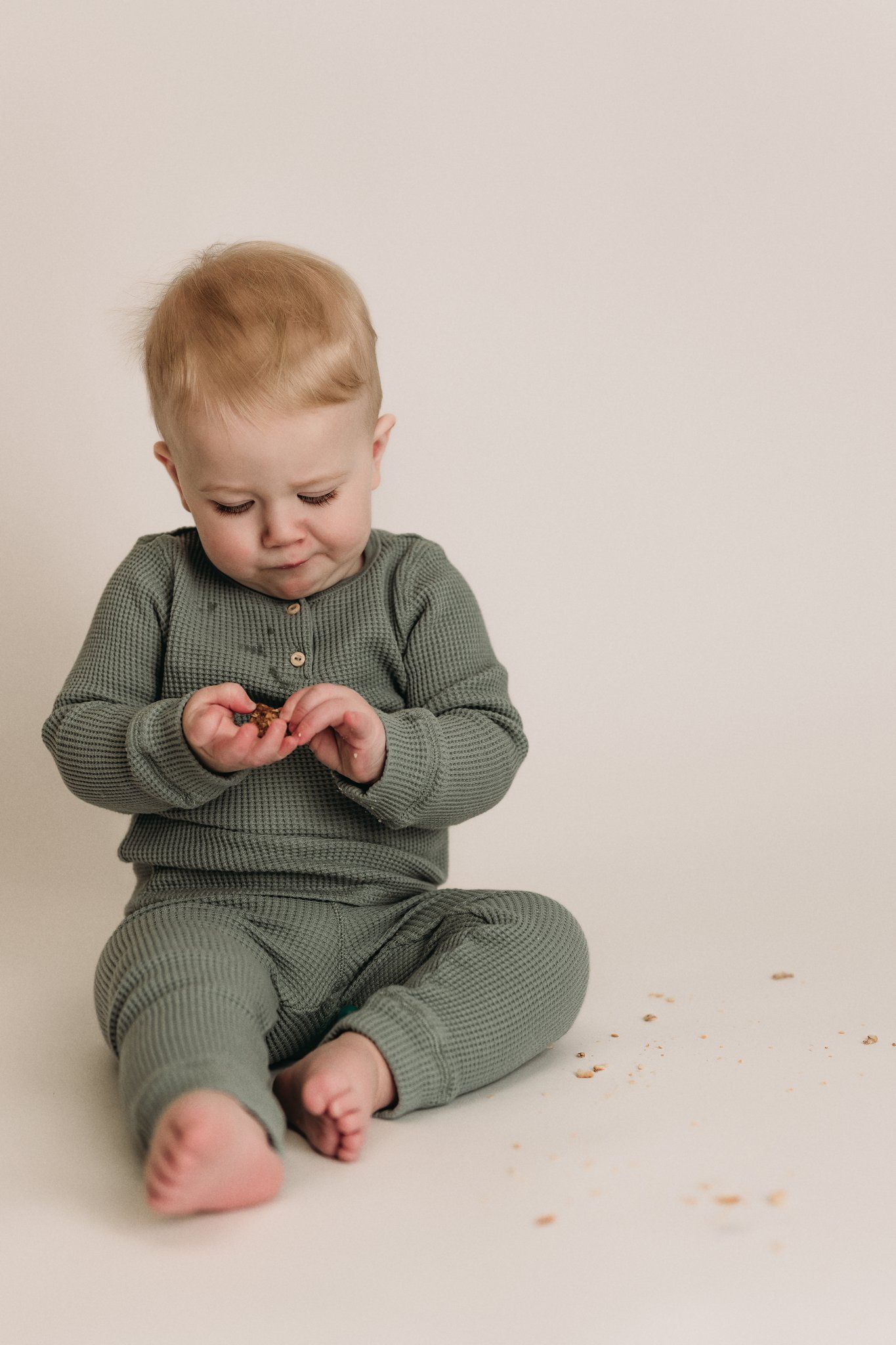 Close up of baby's feet and hands while wearing cozy sage green outfit.