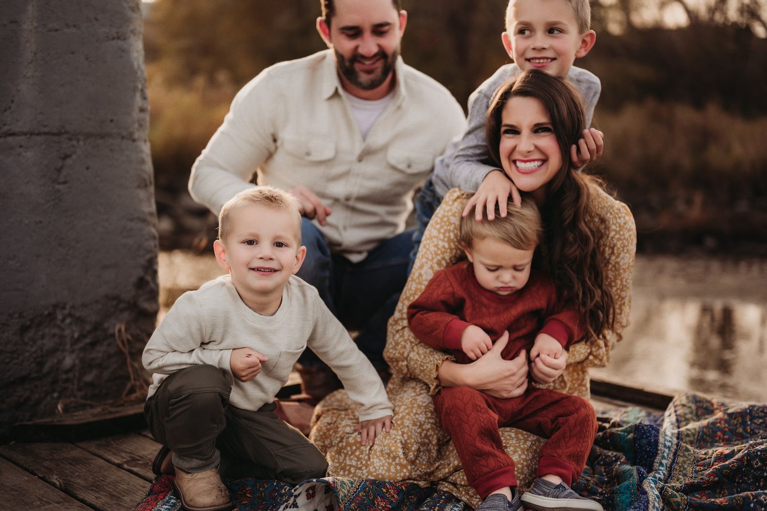 Outdoor family portrait session on rustic deck during golden hour.