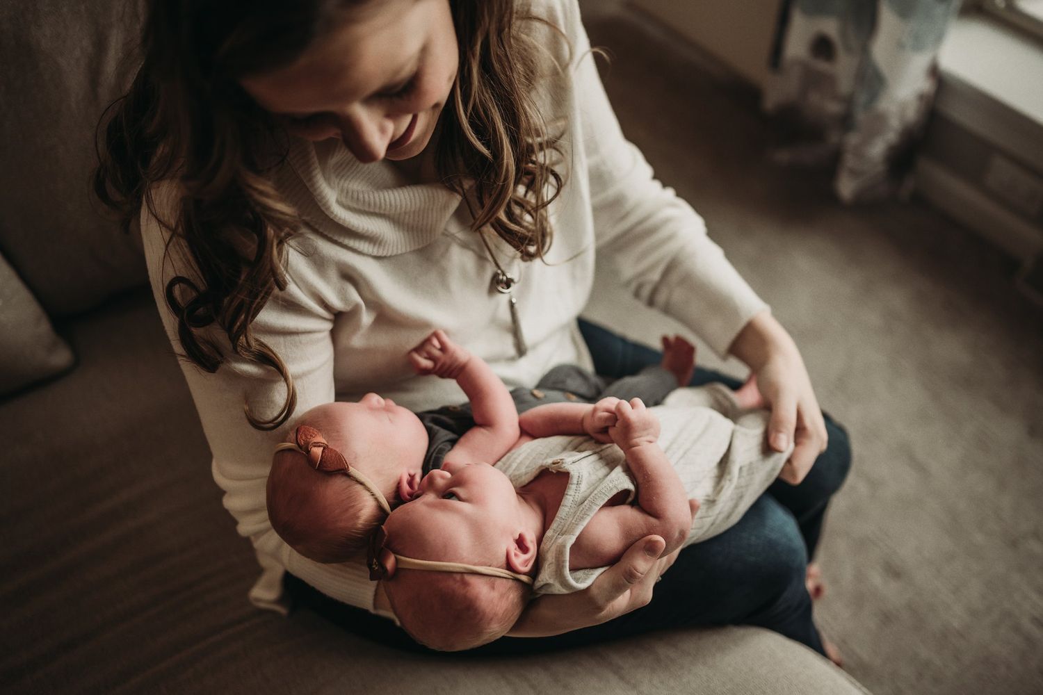 Intimate candid moment of parent holding tiny newborn baby in cozy living room setting.