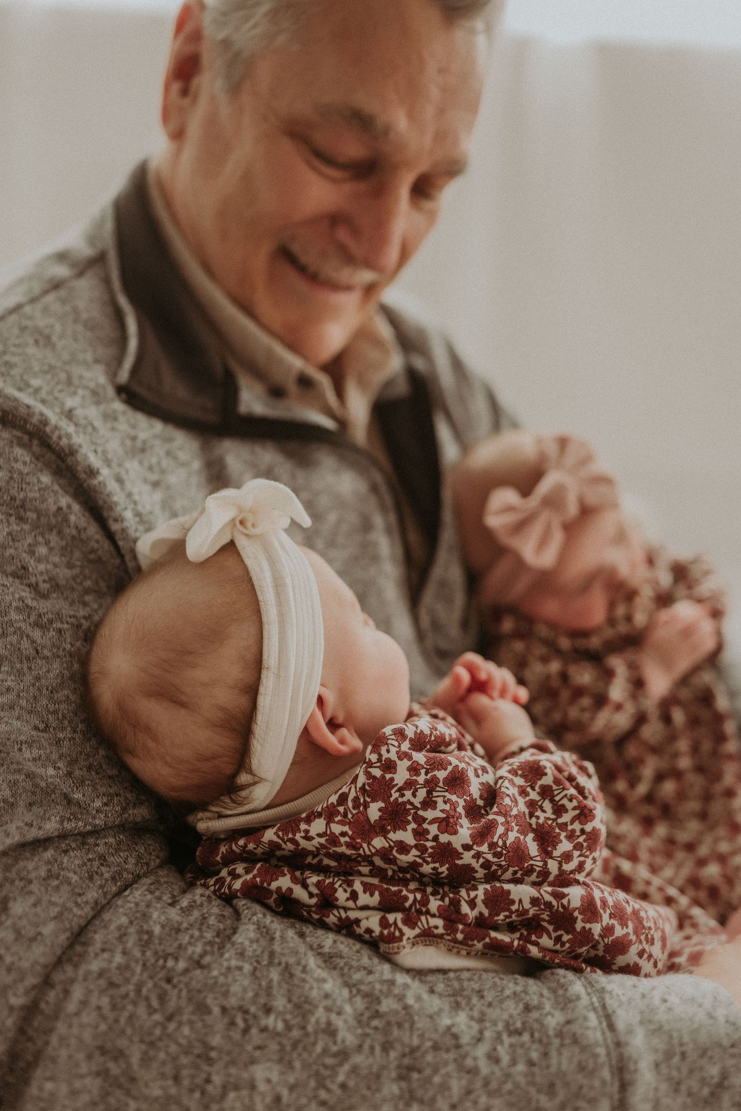 Warm moment captured between adult and sleeping infants in matching floral outfits.