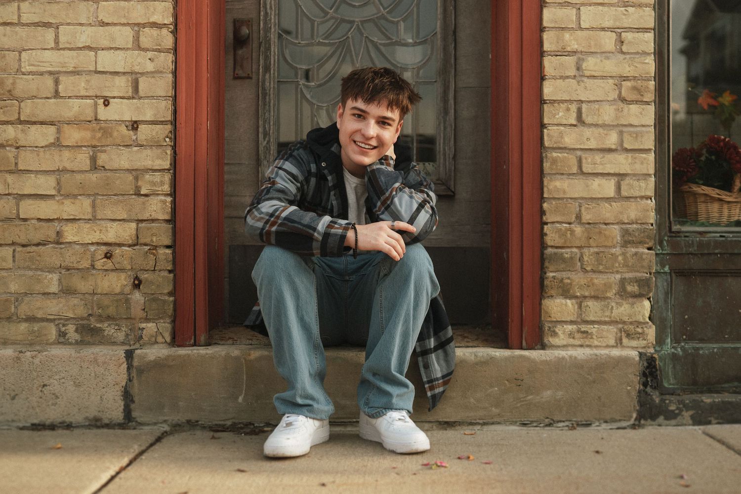 A casual scene showing someone sitting on stone steps against a tan brick wall with ornate windows.