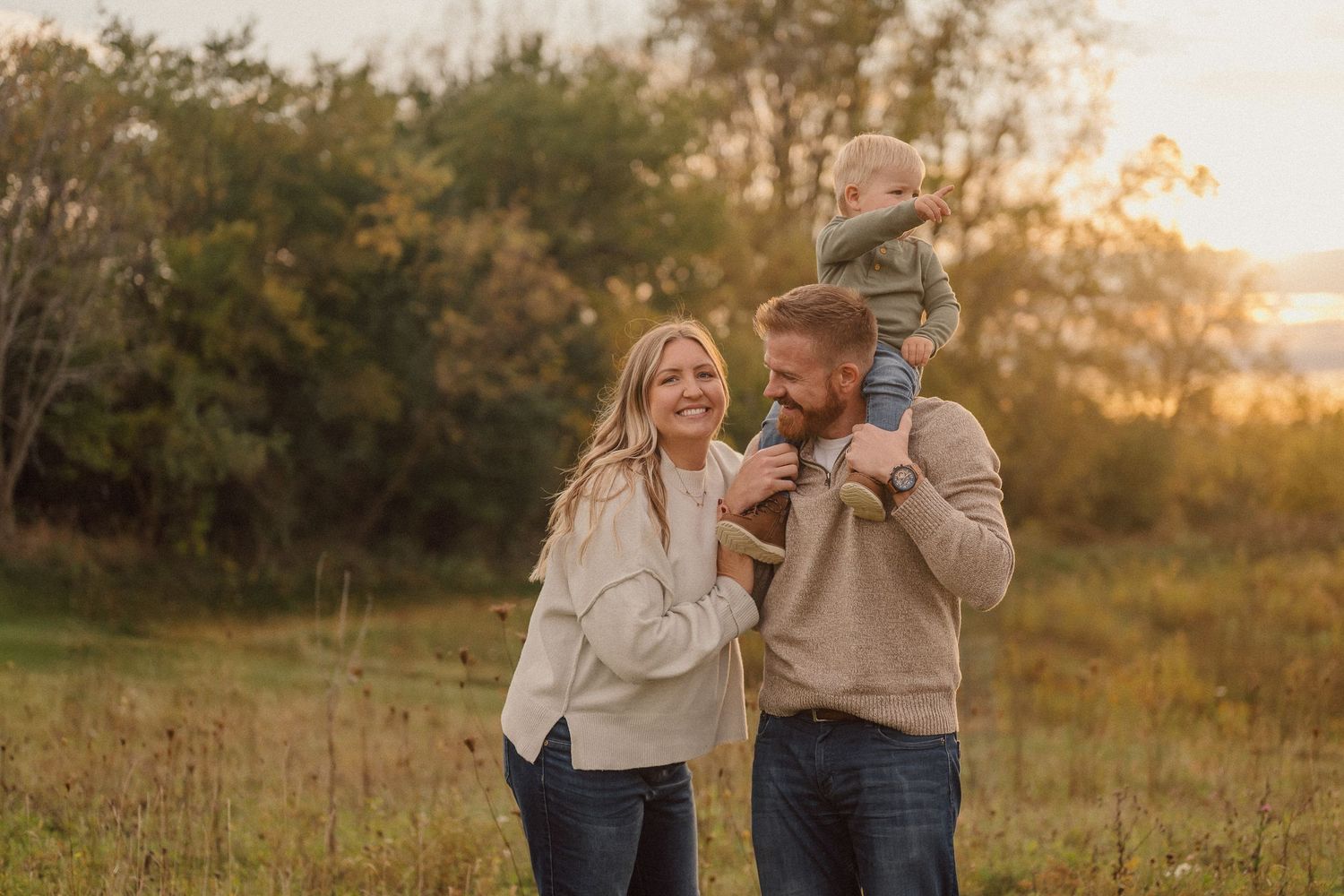 Family enjoying a tender moment together in a sunlit meadow during golden hour.