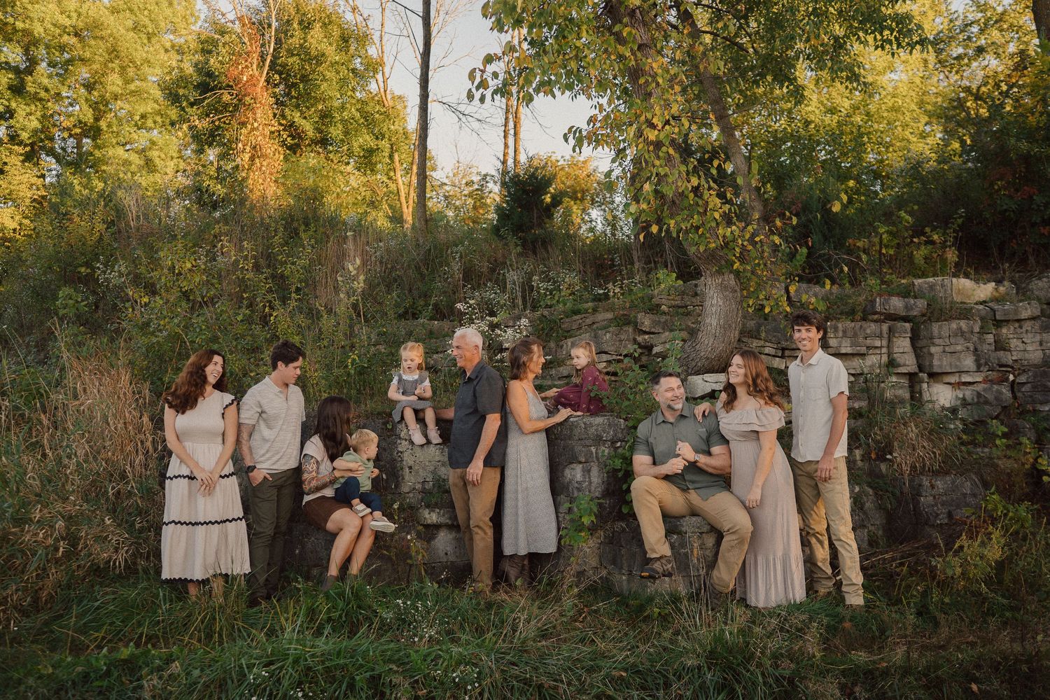 Large group gathered for outdoor photos on stone wall during sunset.