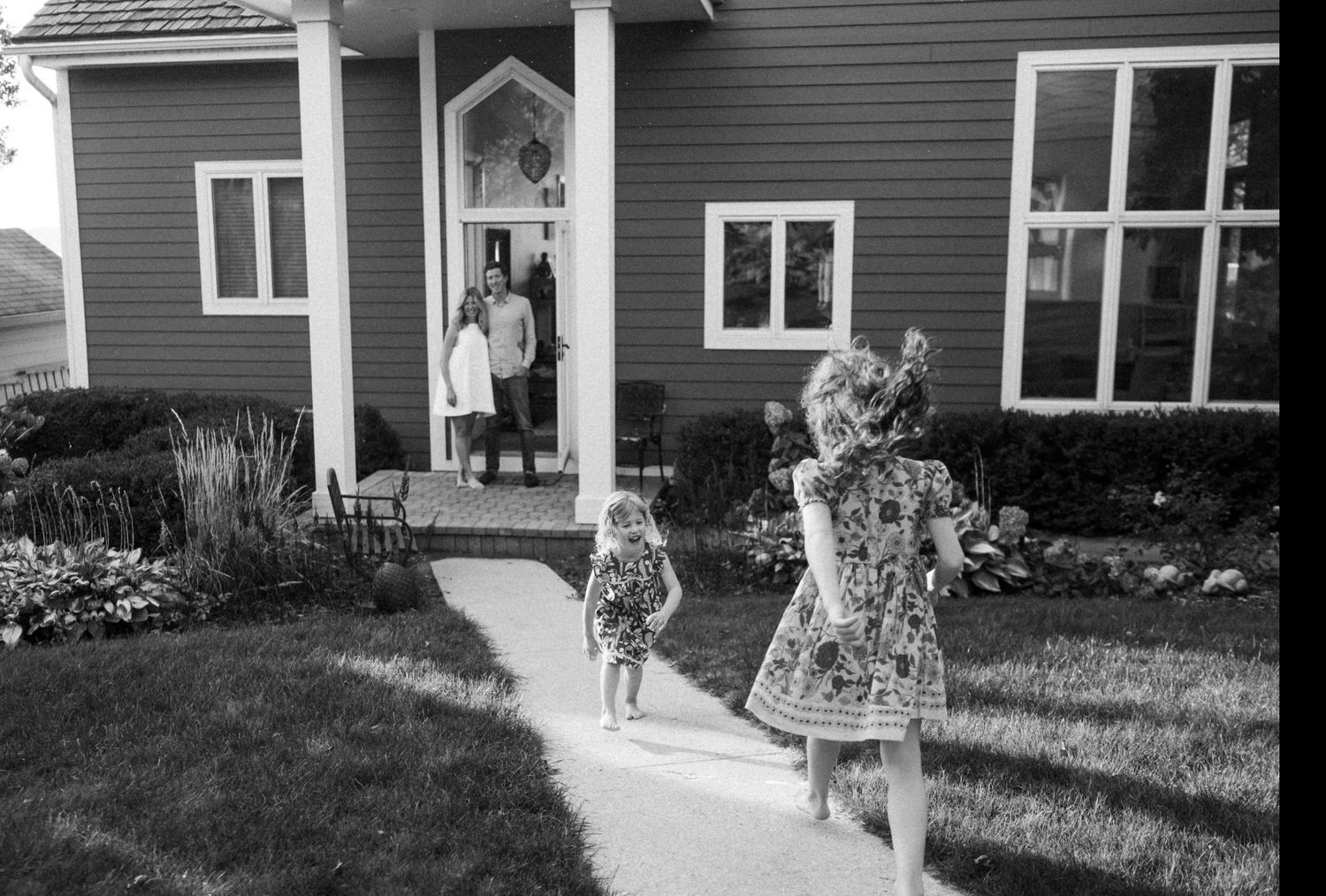 A vintage black and white photograph showing a family standing in front of their suburban home.