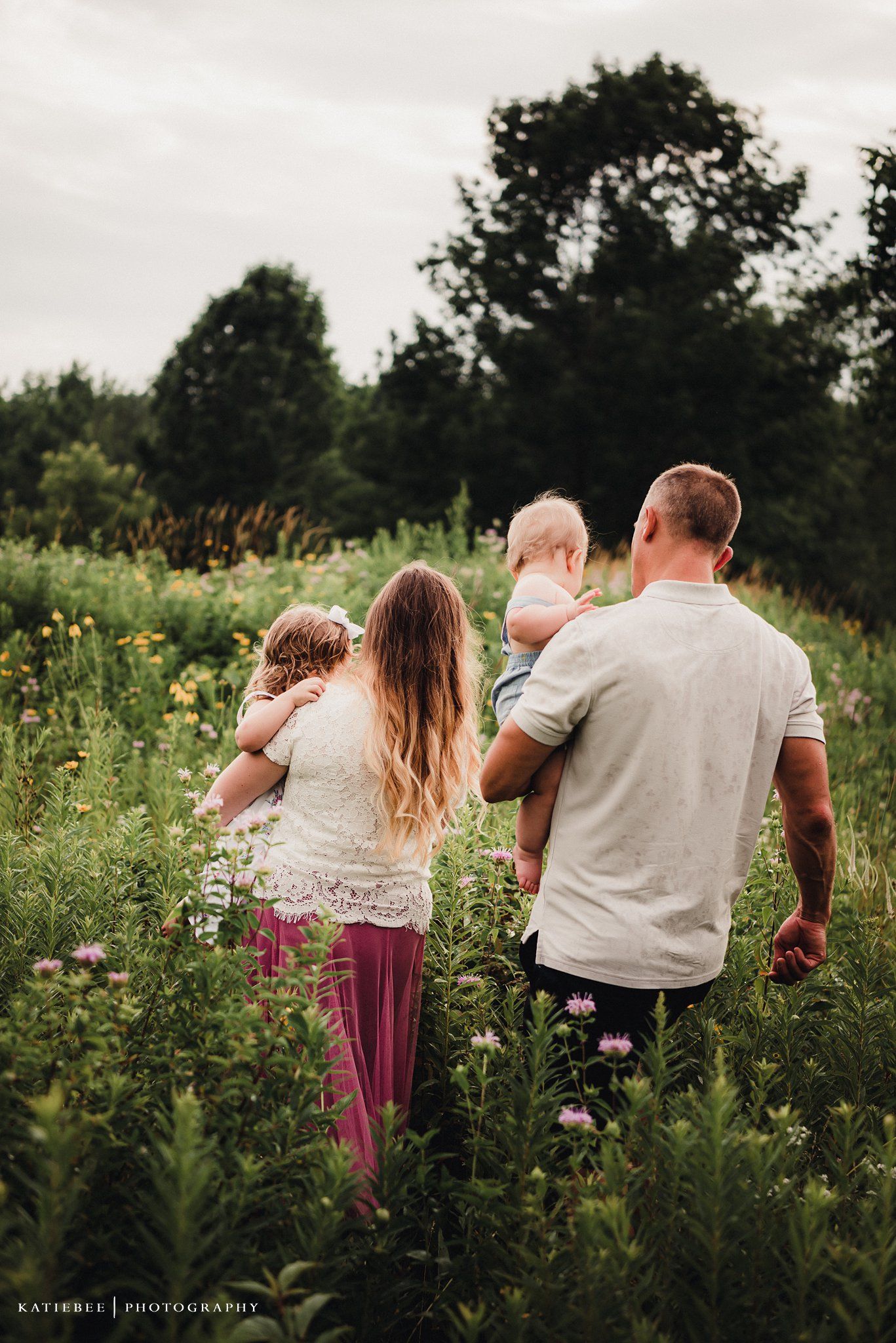 A family walks together through a blooming summer meadow with wildflowers.