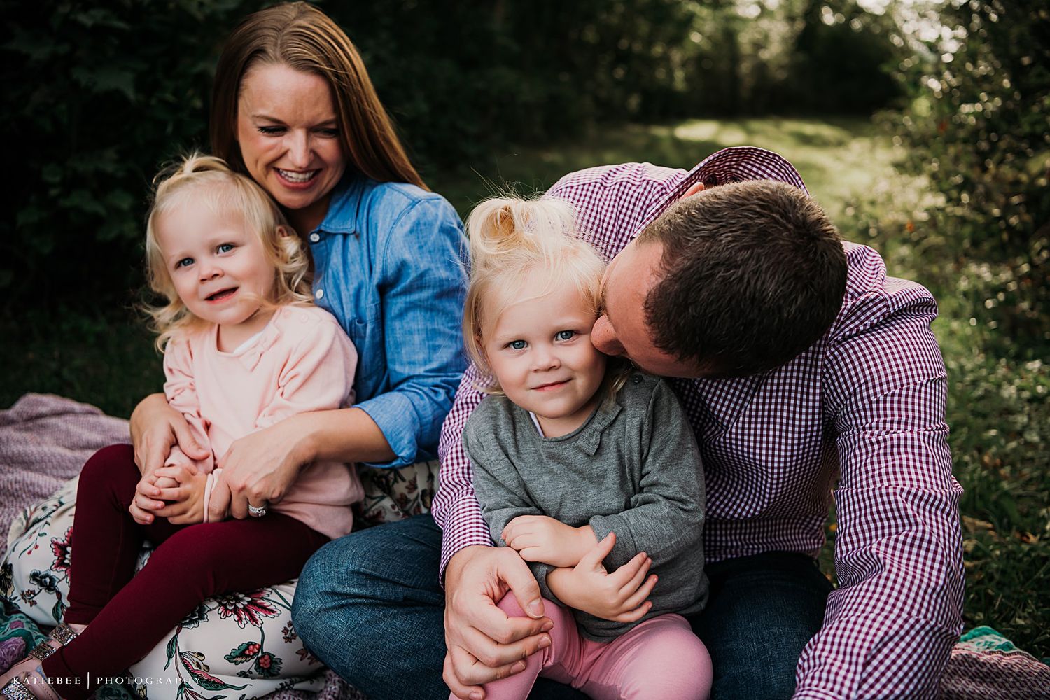 Family of four shares intimate moment together during outdoor photo session.