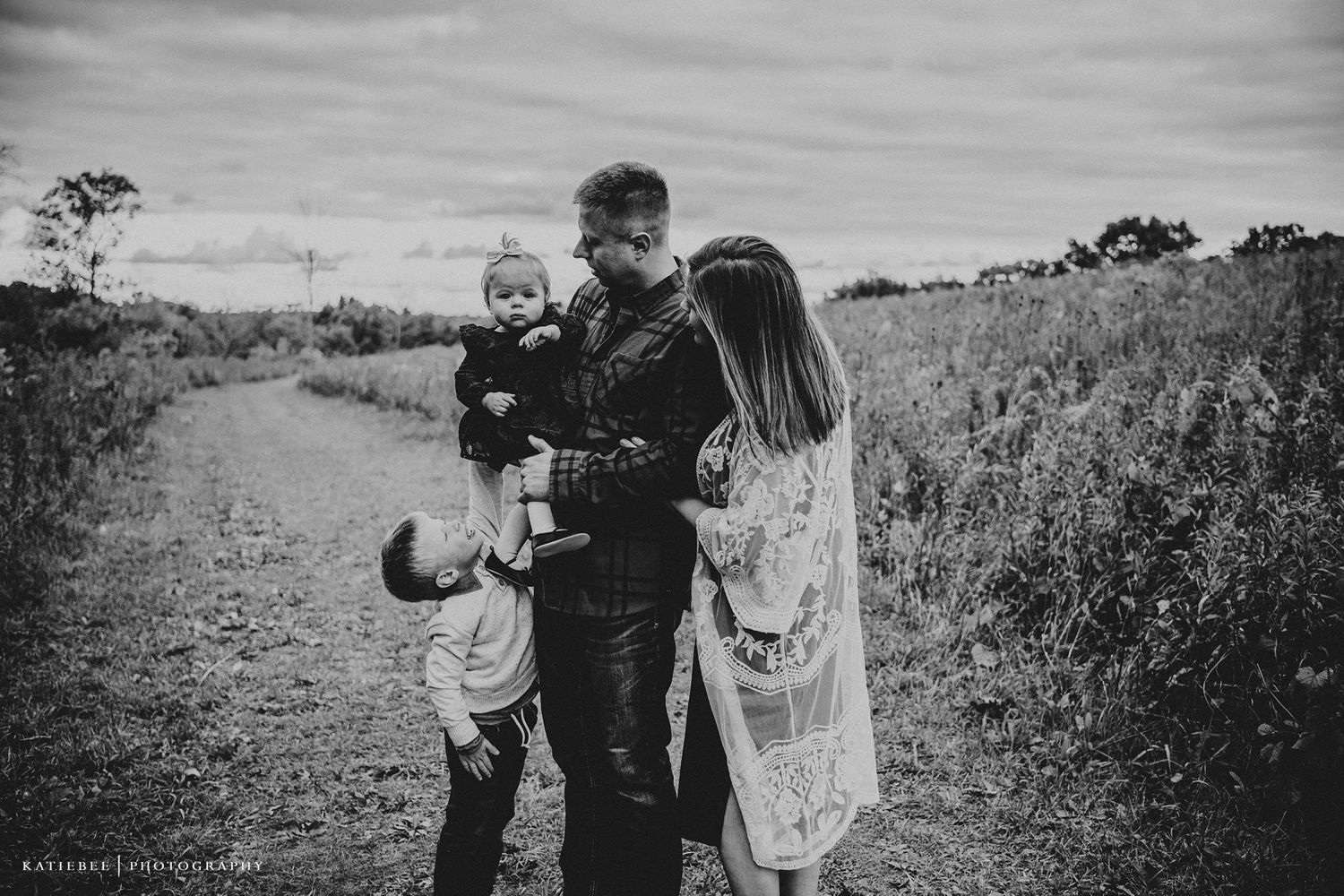 Black and white photo of family walking together on rural country path.