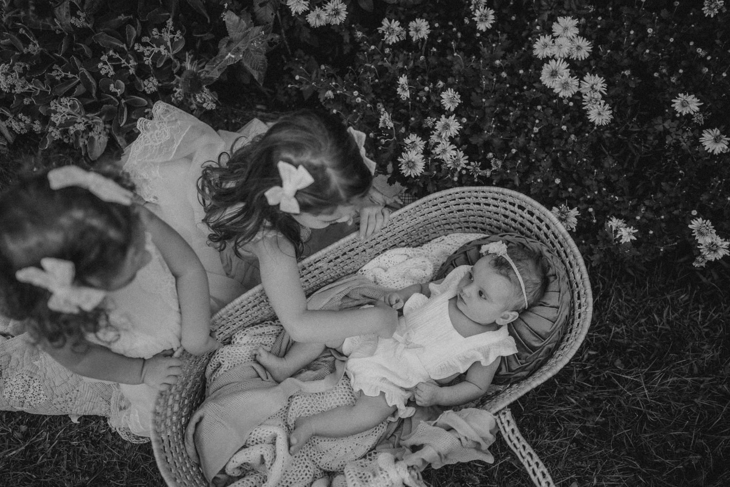 Black and white photo of a woven basket scene with flowers in background.