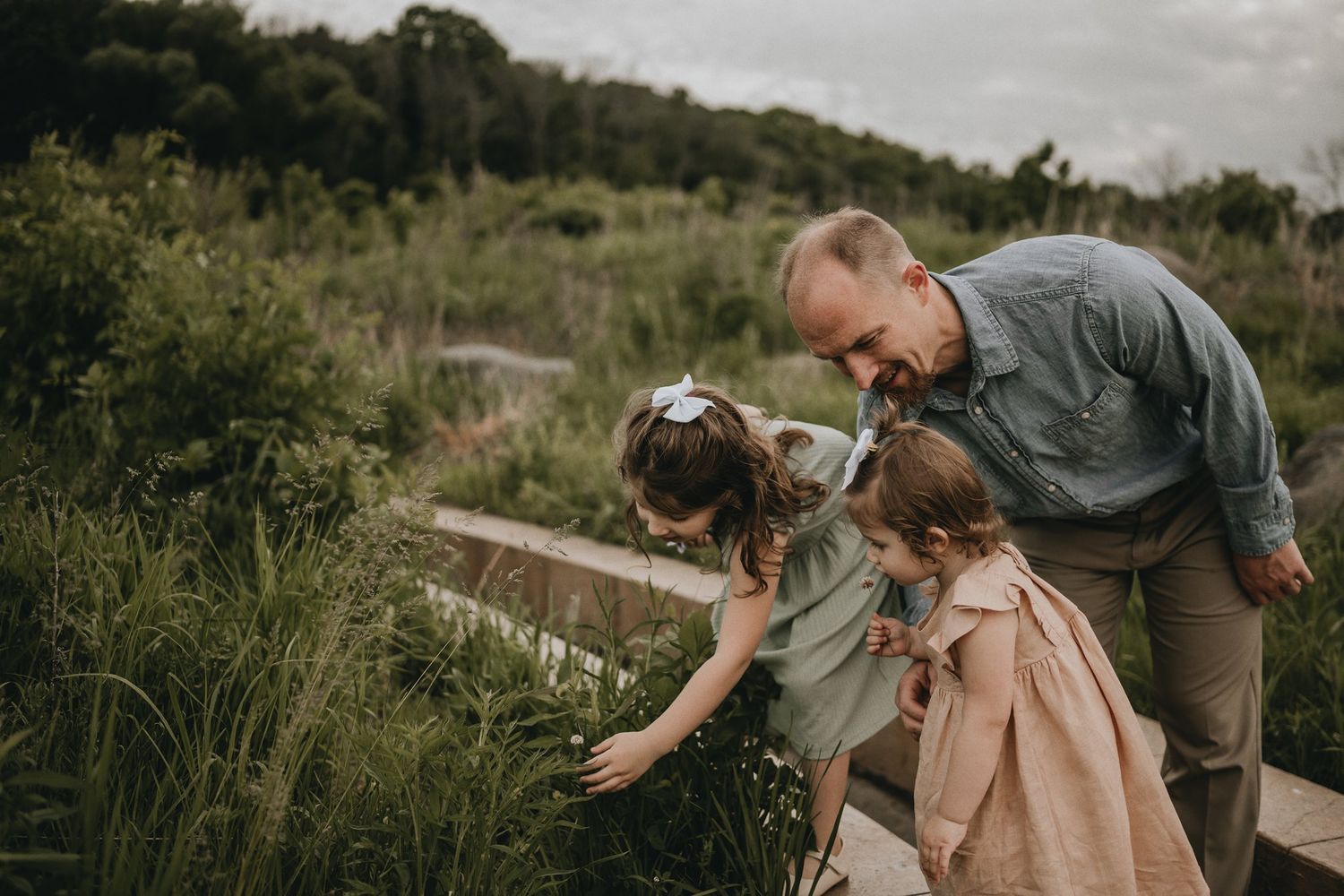 An intimate family moment exploring nature together along a wooden path.