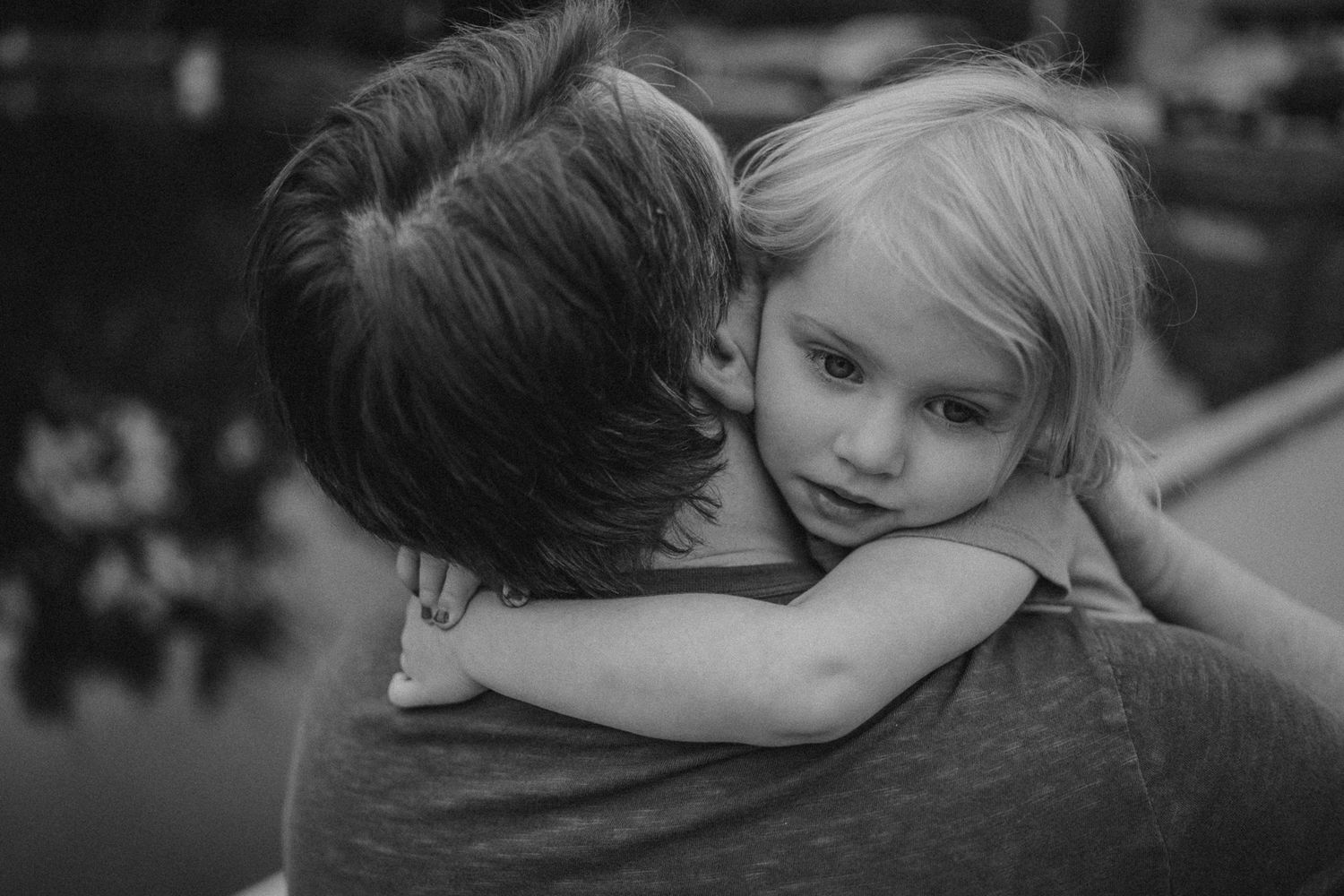 Sweet embrace captured in black and white on a wooden dock by the water.
