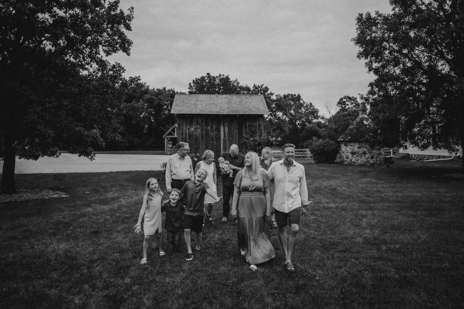 Group walking together across grassy field with trees and building in background.