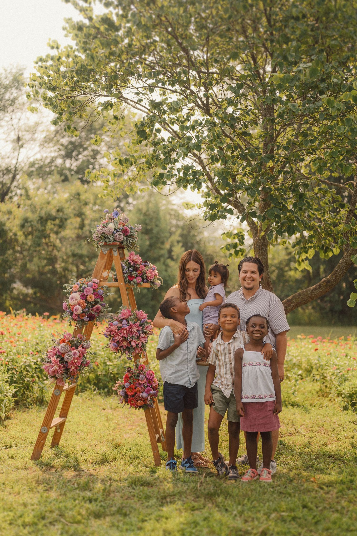 Group photo of family members gathered under a wooden arch decorated with vibrant pink flowers in a garden.