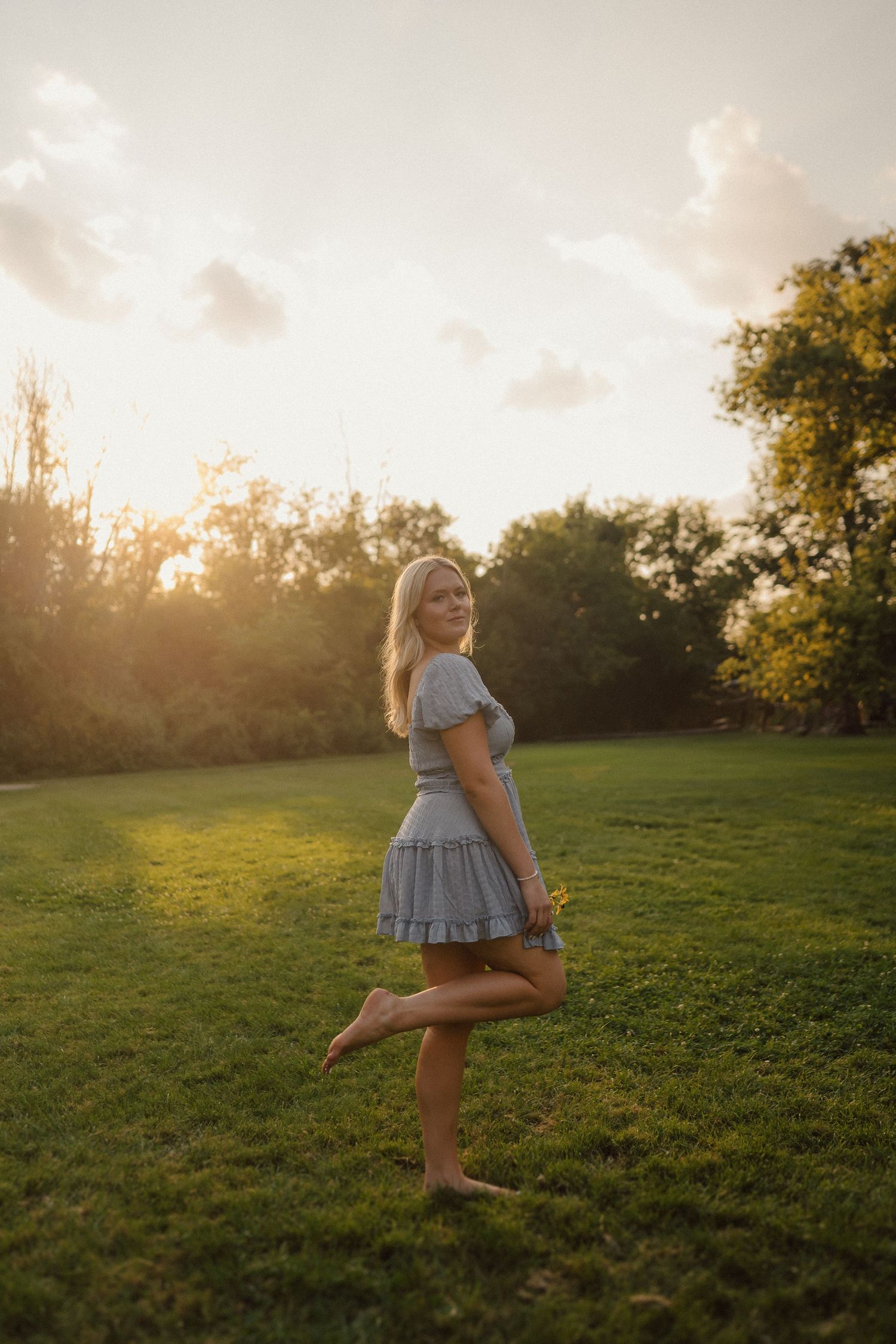 Person dancing and twirling in a sundress at golden hour in a grassy field.