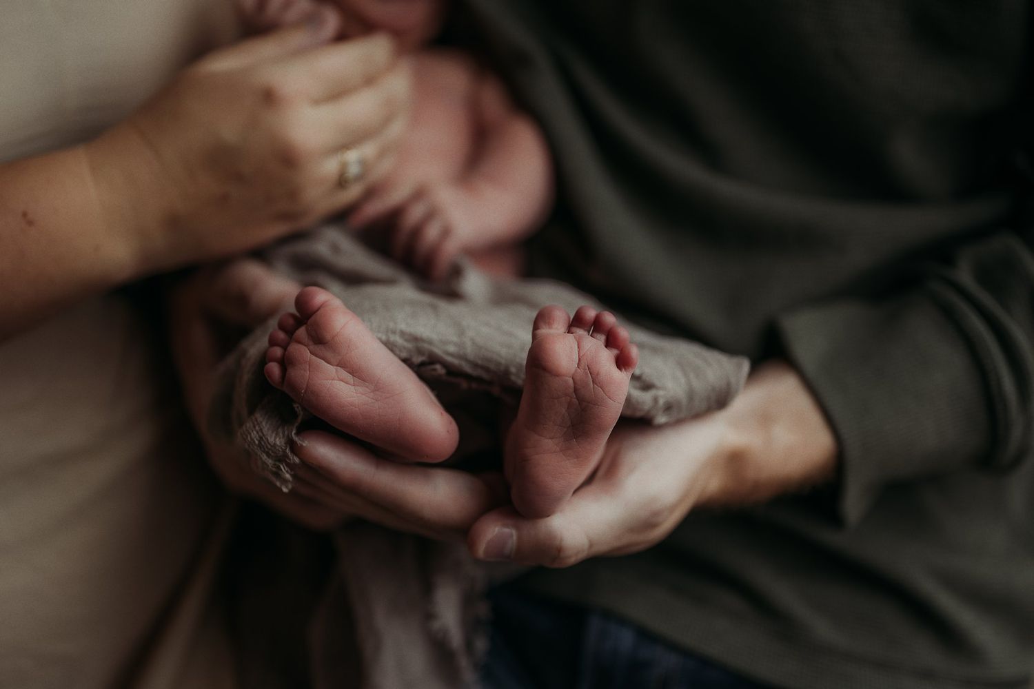Close-up of tiny baby feet resting on parent's hands.